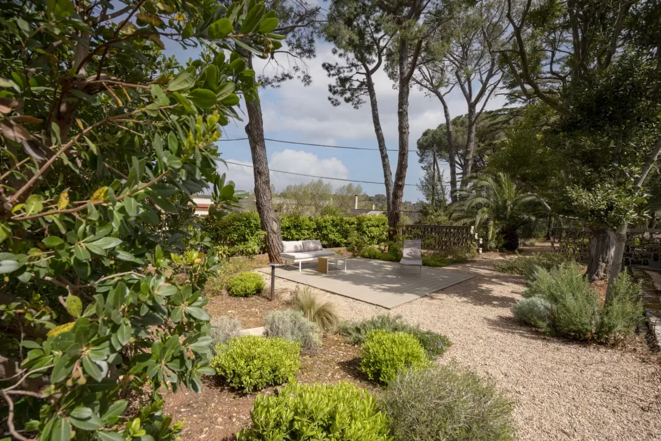 A landscaped garden patio with outdoor seating and surrounding trees.