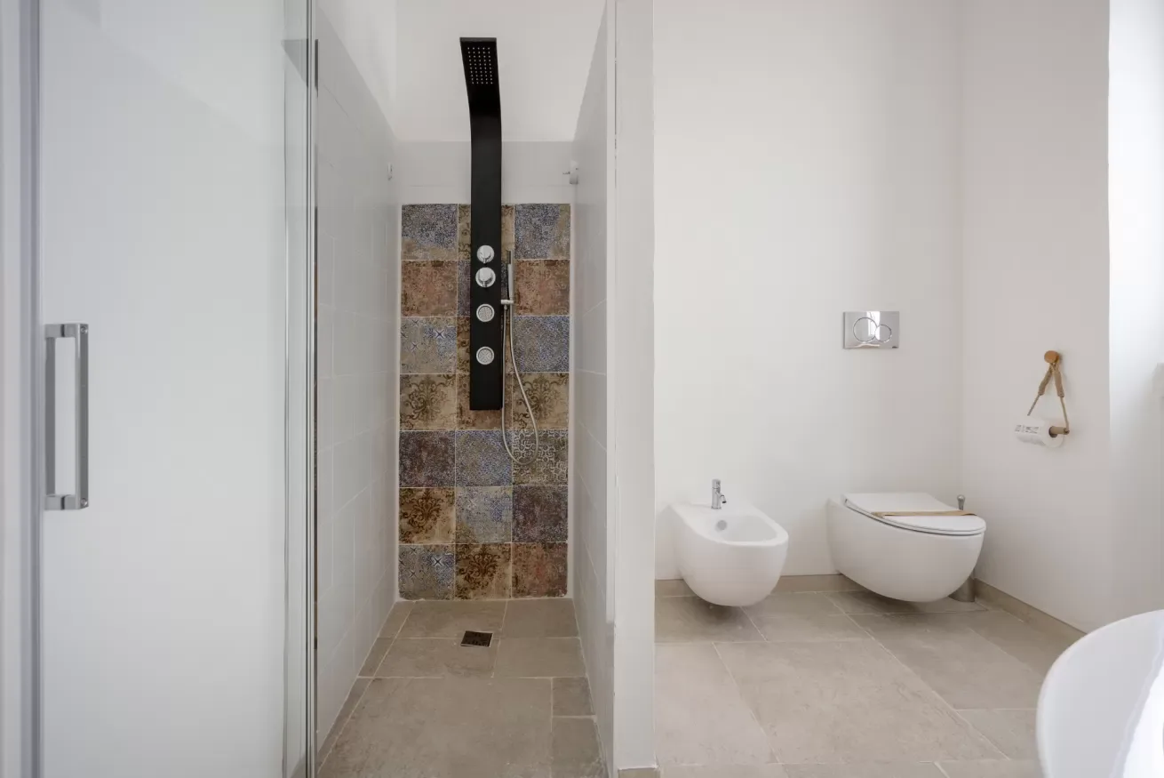 A modern bathroom with a walk-in shower, wall-mounted showerhead, and toilet.