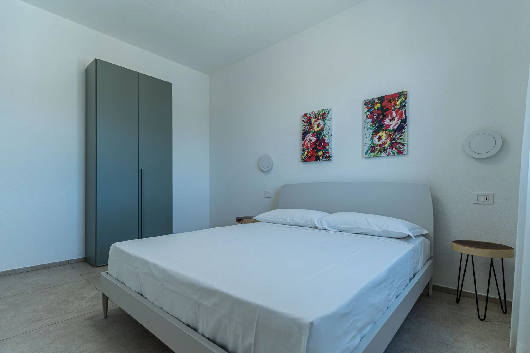 A bedroom with a neatly made bed and colorful wall art.