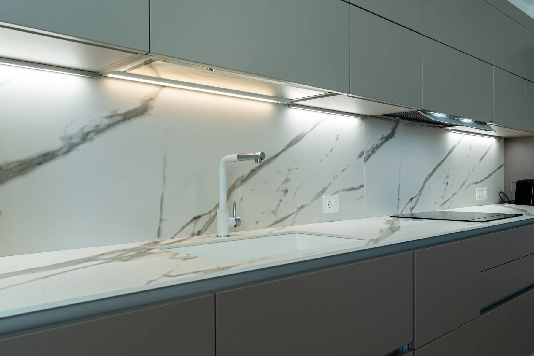 A modern kitchen counter with a sink beneath sleek cabinets.