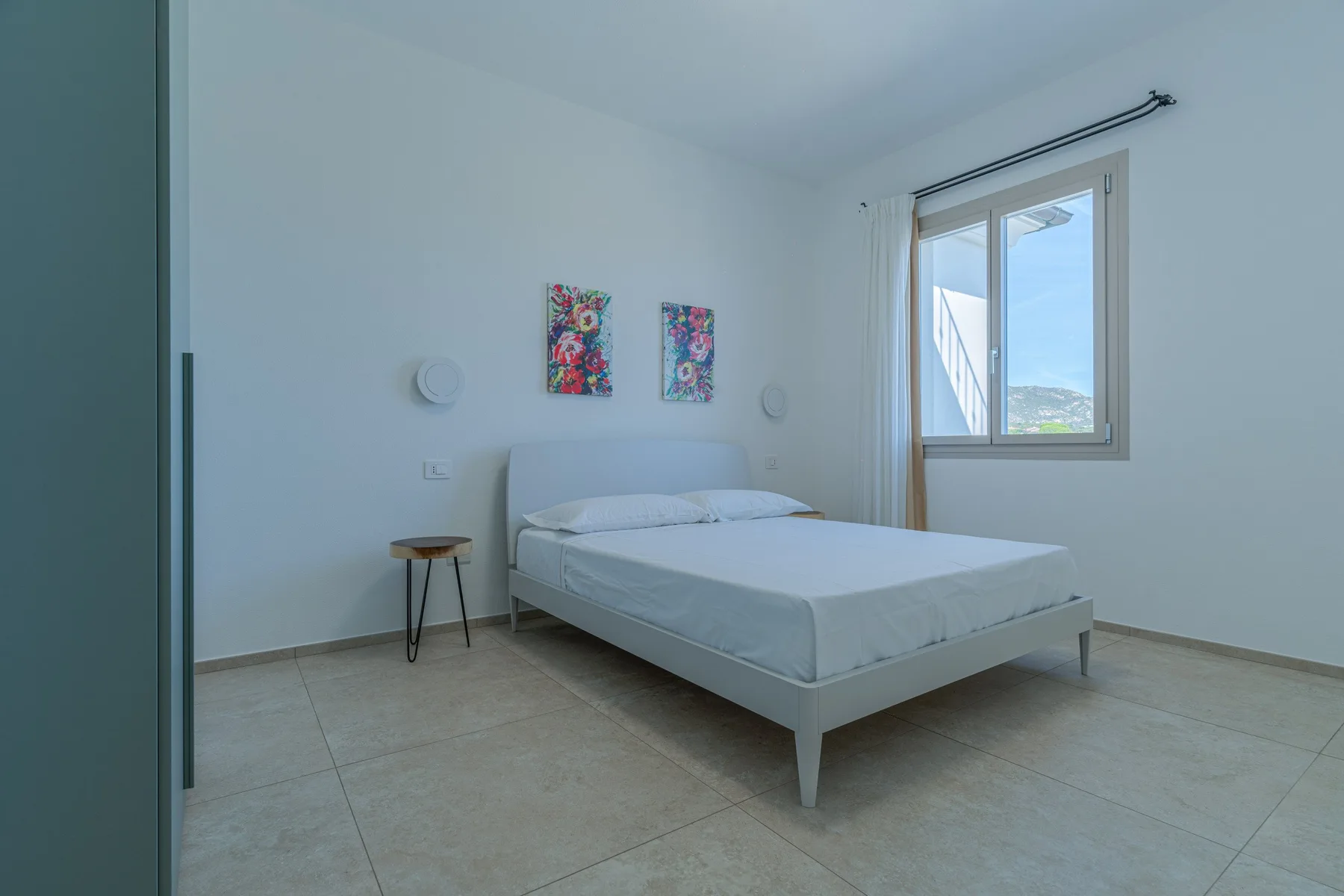A bright bedroom with a neatly made bed and a window.