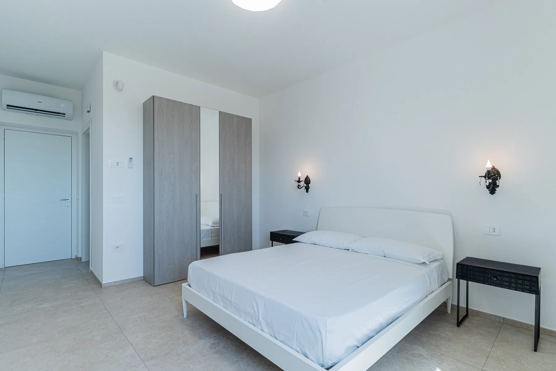 A bright bedroom with a bed and a wardrobe against the wall.