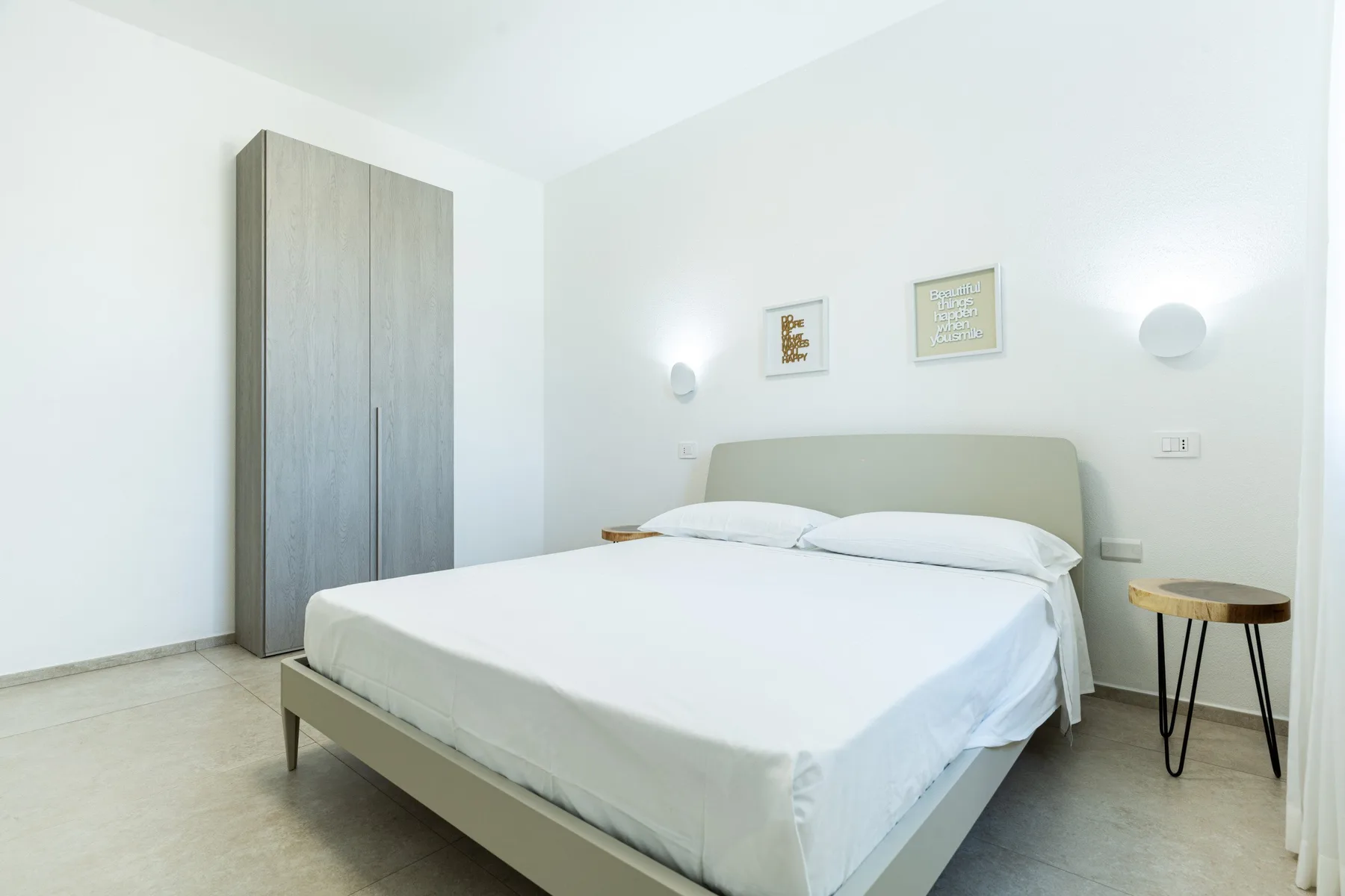 A bright bedroom with a neatly made bed and a tall wardrobe.