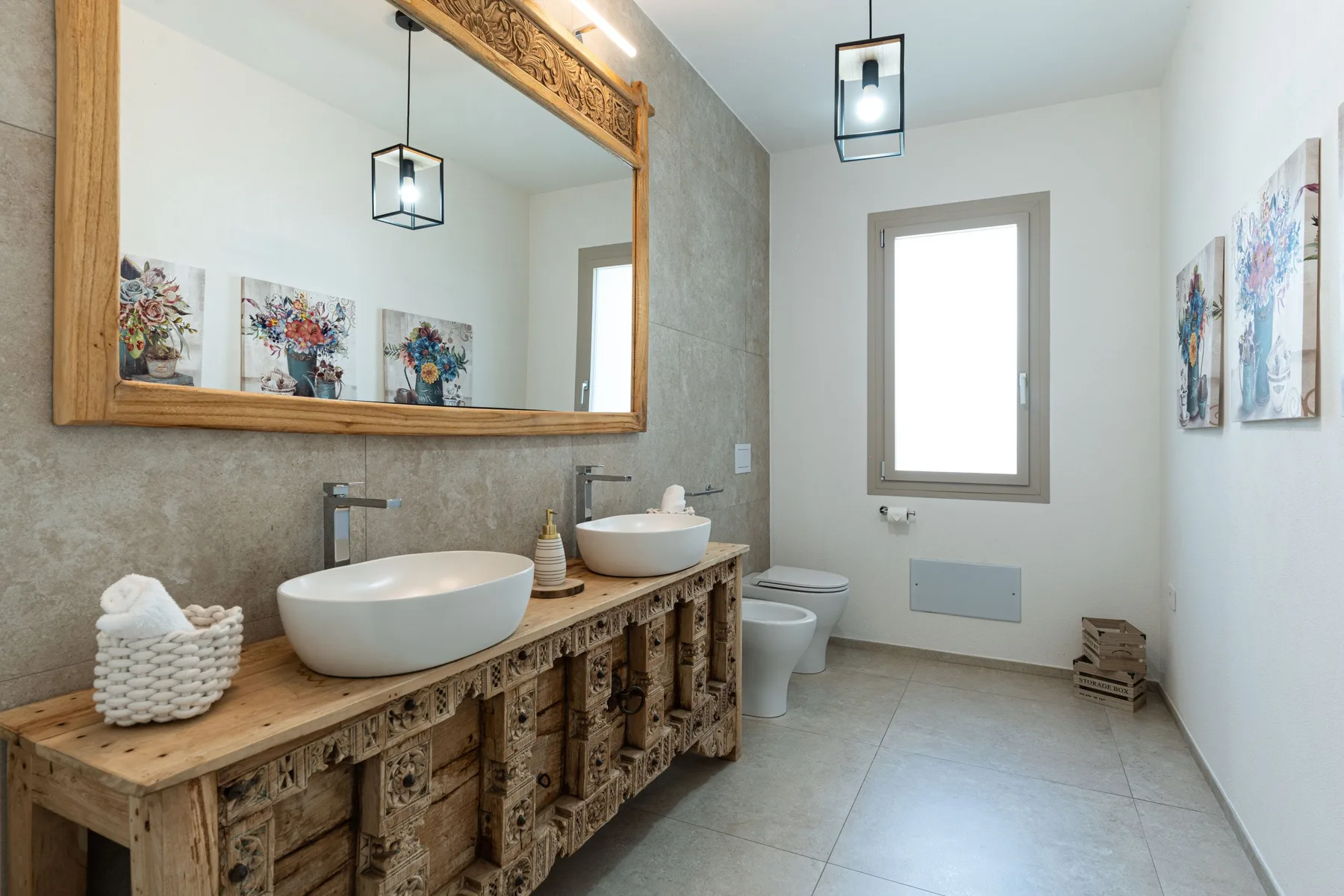 A bathroom with a long wooden vanity, two vessel sinks, and a window.
