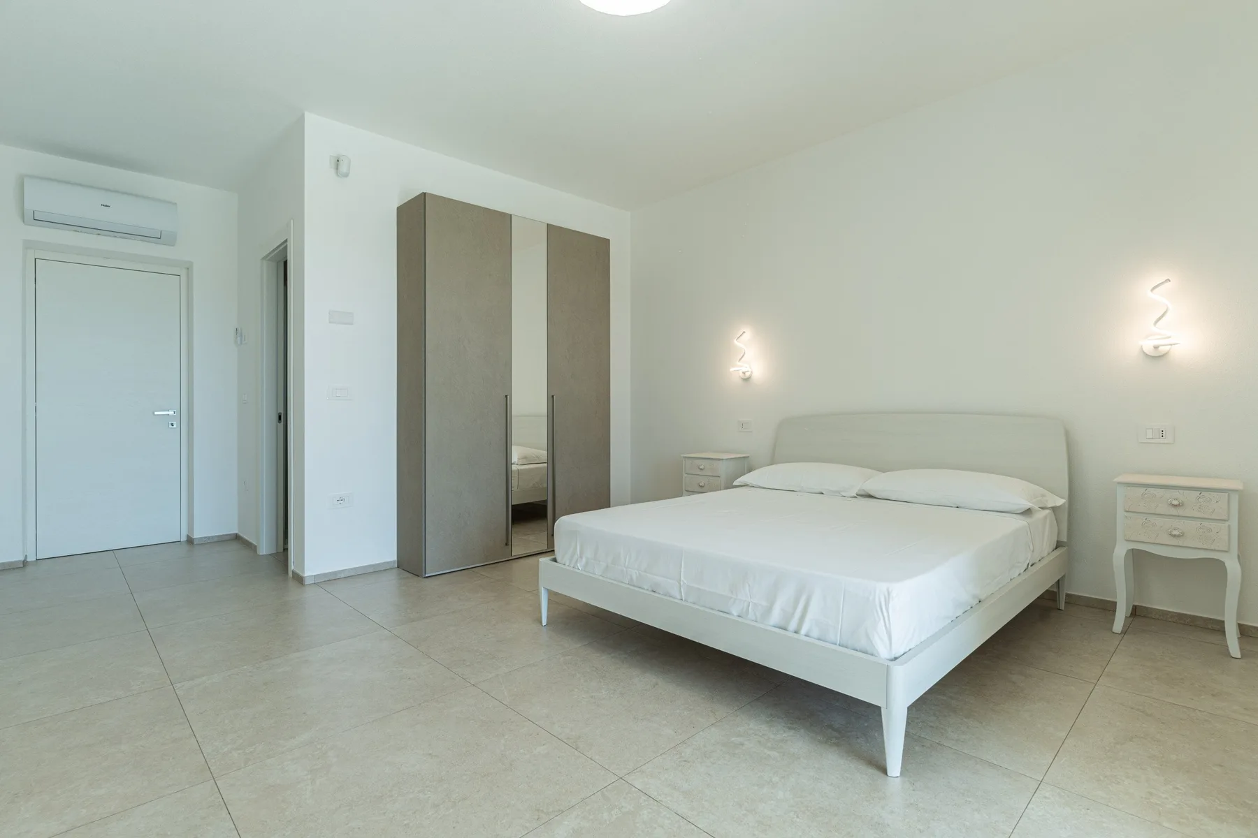 A bright bedroom with a bed and a tall wardrobe.