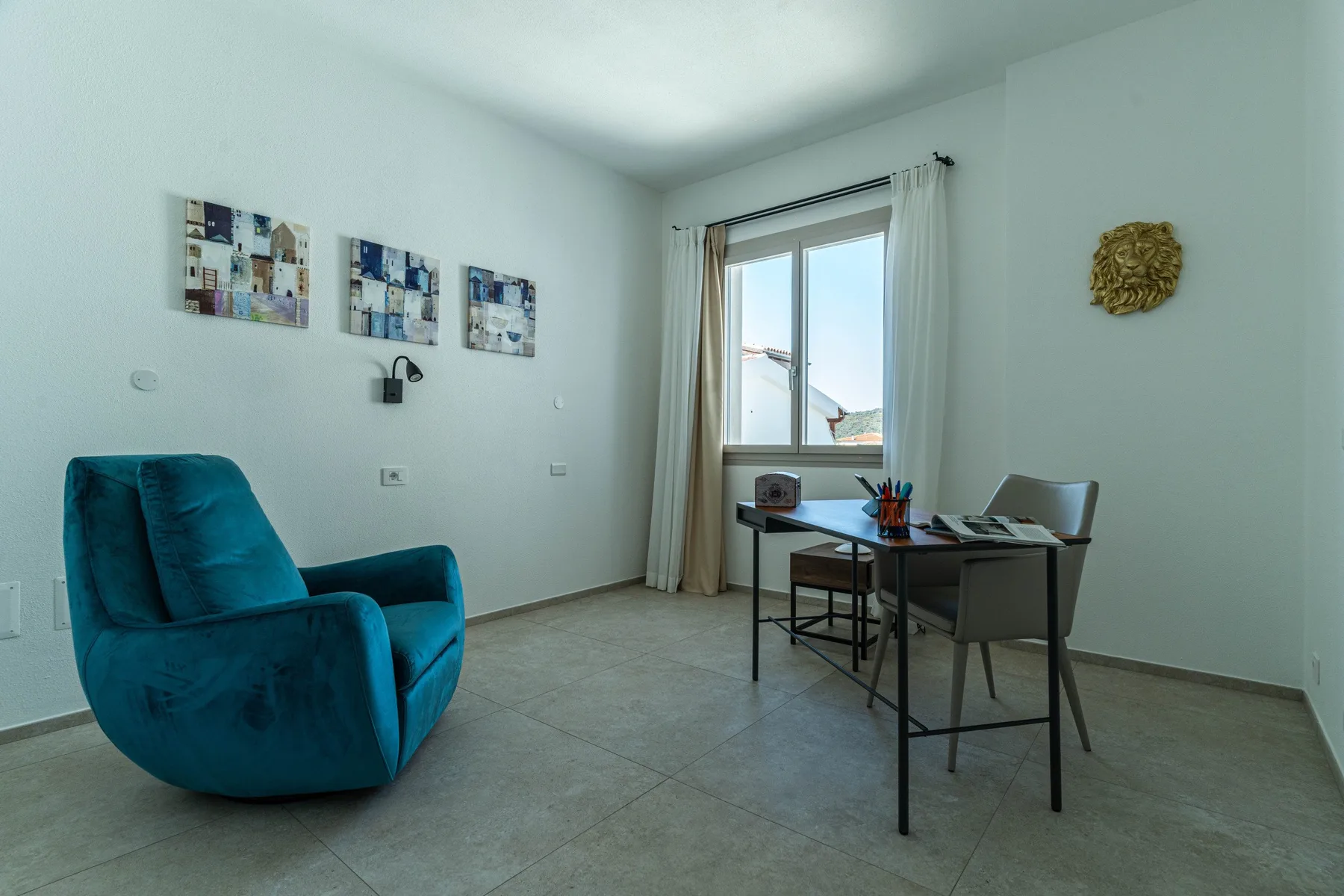 A bright room with a desk and seating beside a large window.