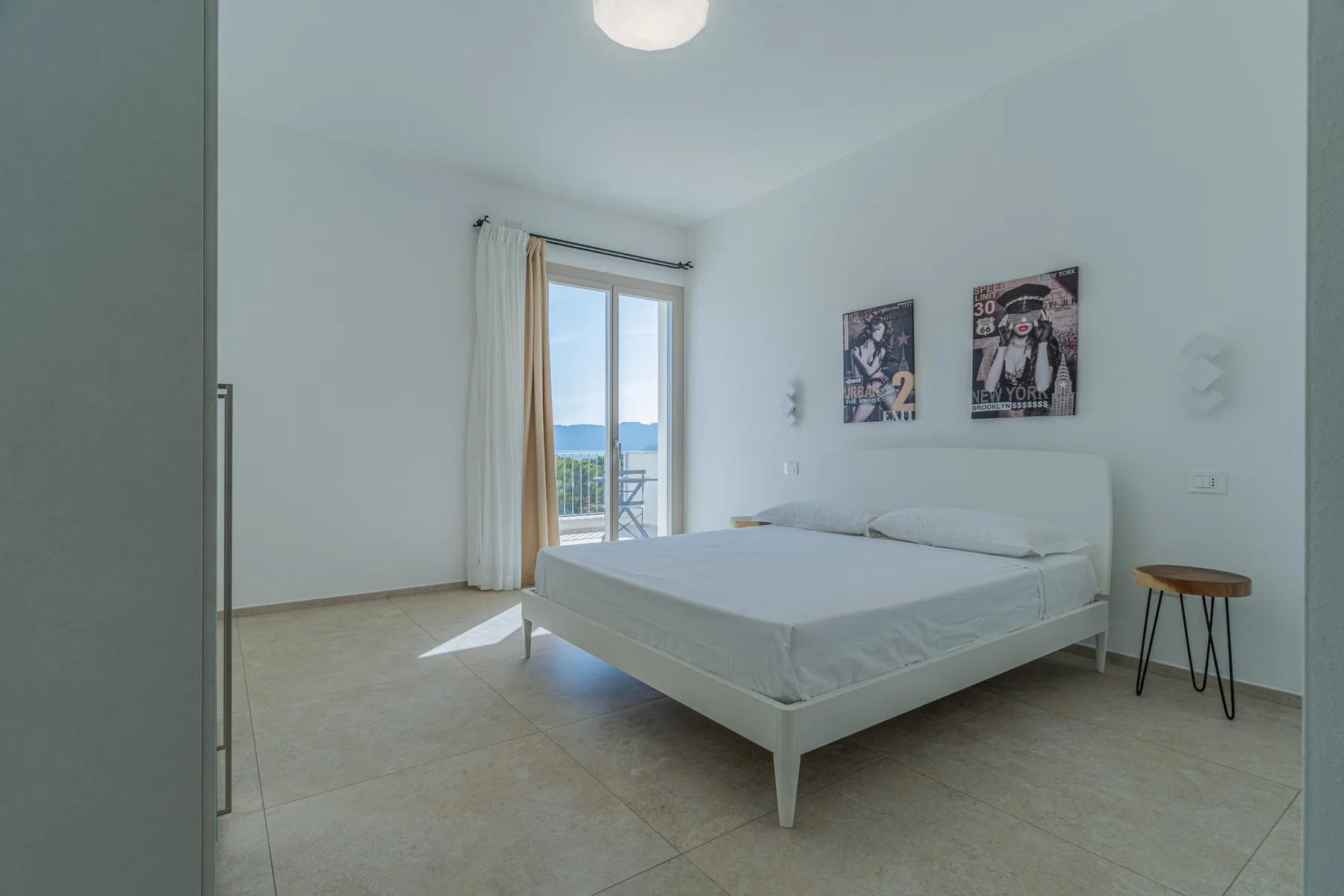 A bright bedroom with a bed beside a glass balcony door.
