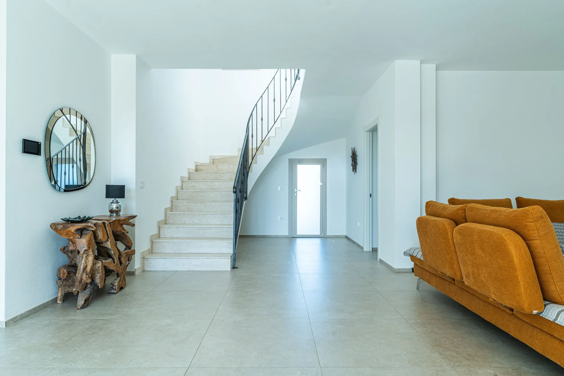 A bright entry hall with a staircase and orange seating.