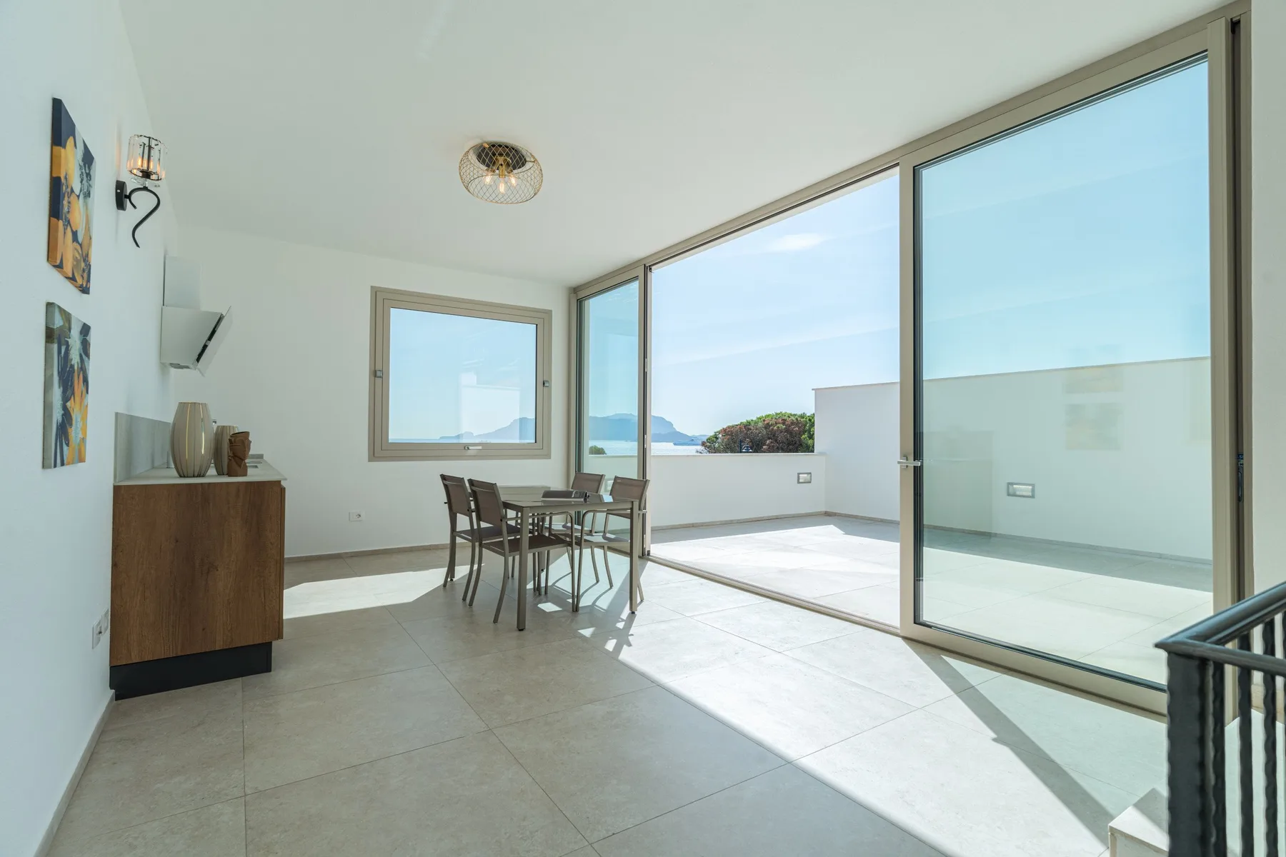 A bright dining area opens onto a terrace through large glass doors.
