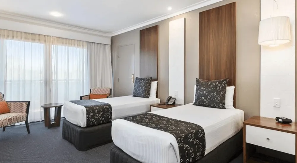 Habitación de hotel con dos camas individuales y vistas al balcón.