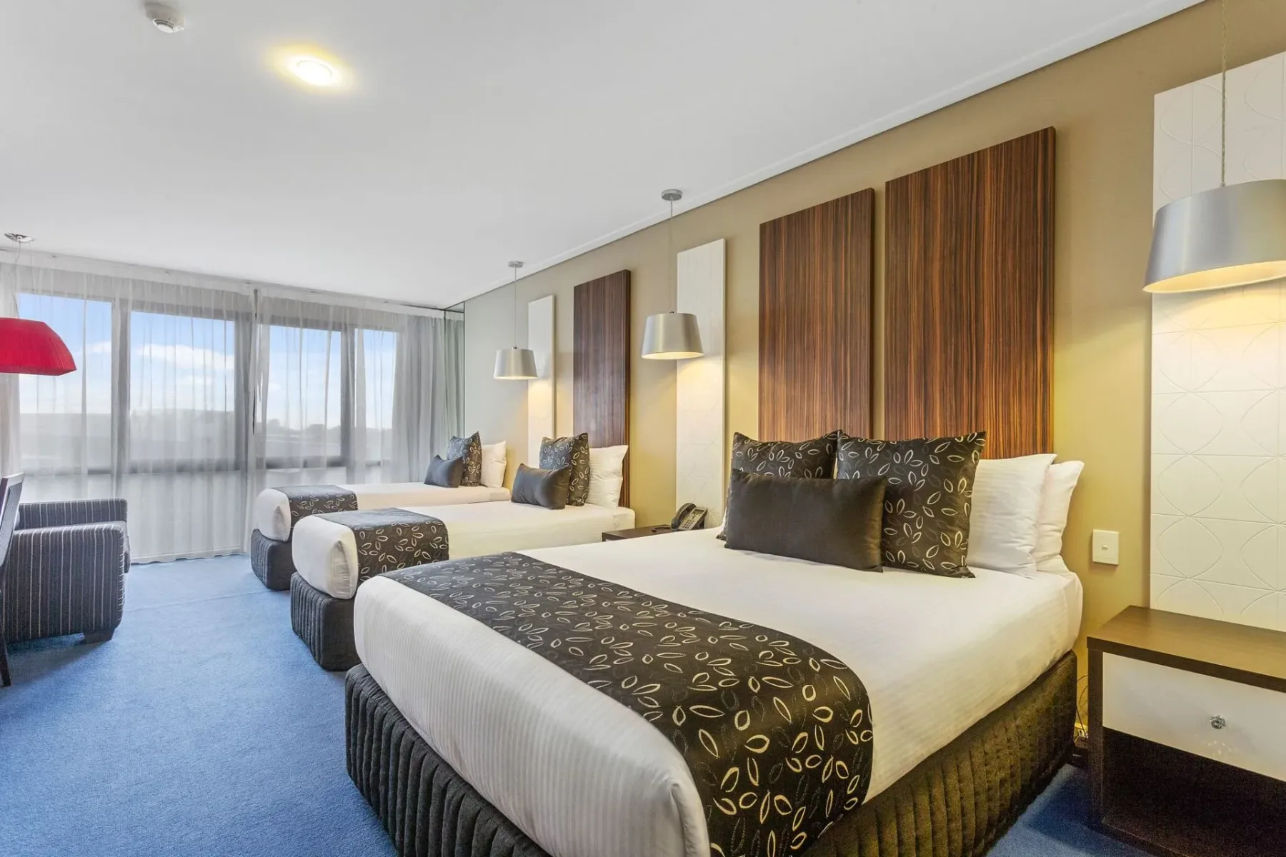 Habitación de hotel con dos camas y cabeceros marrones.