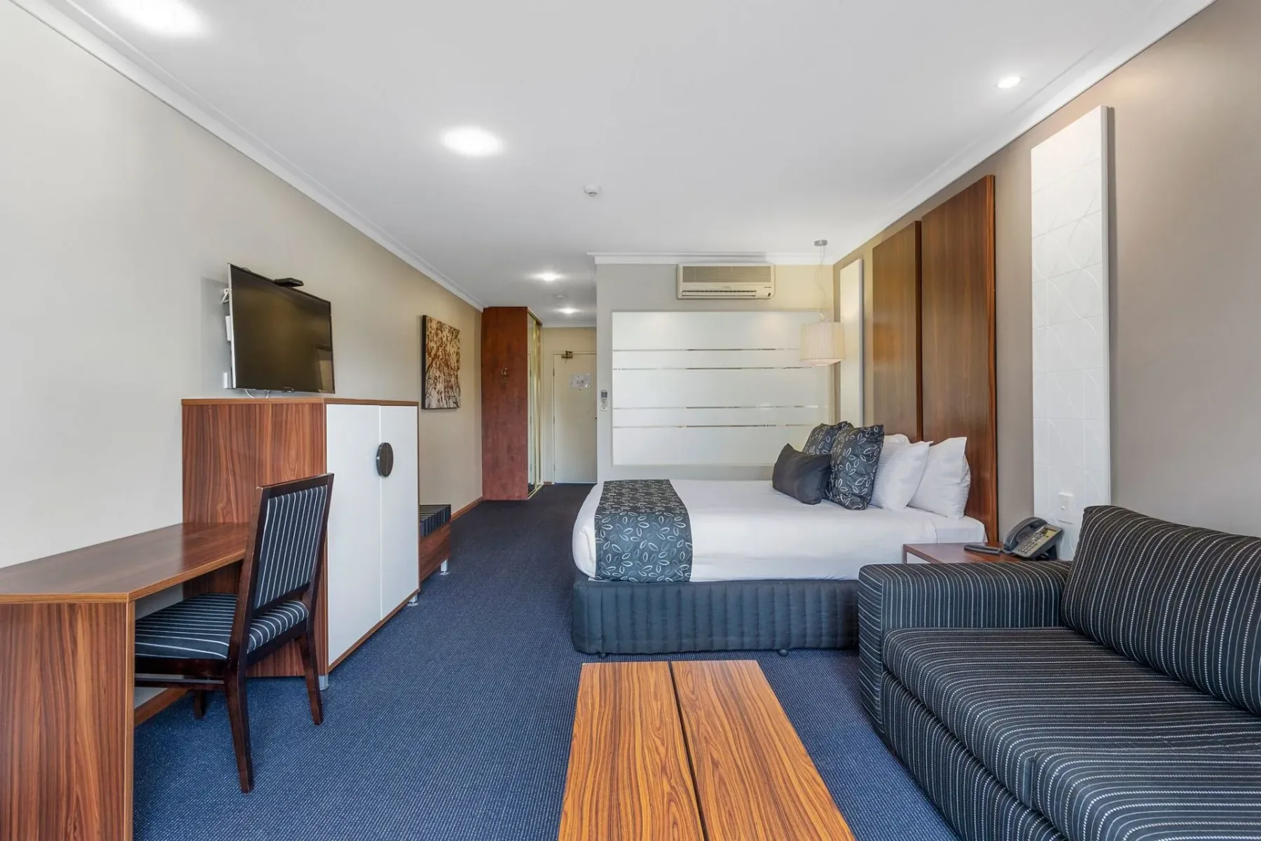 Habitación de hotel con una cama, sofá, escritorio y televisor.