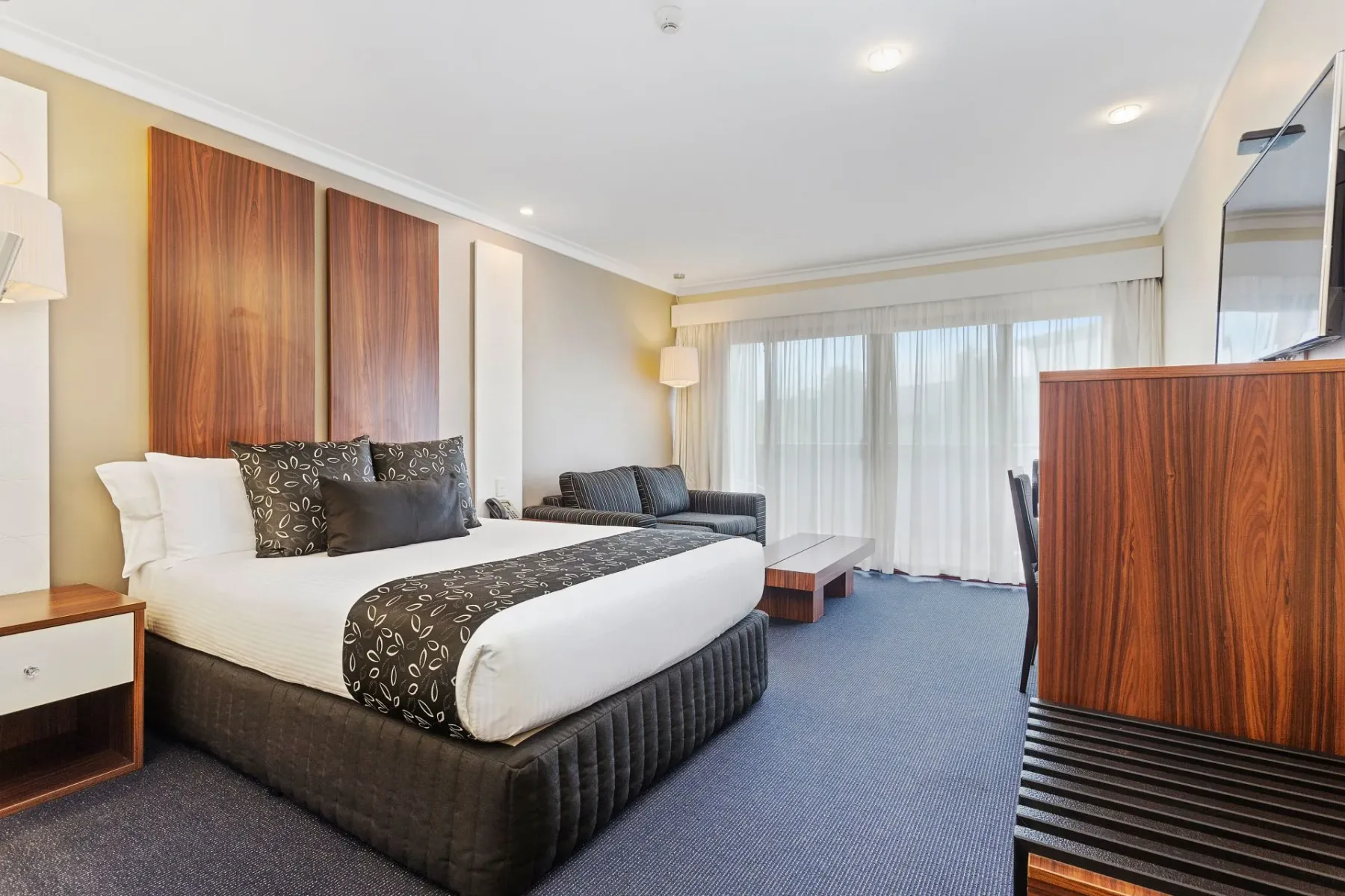 Habitación de hotel con una cama king size, sofá, escritorio y ventana.