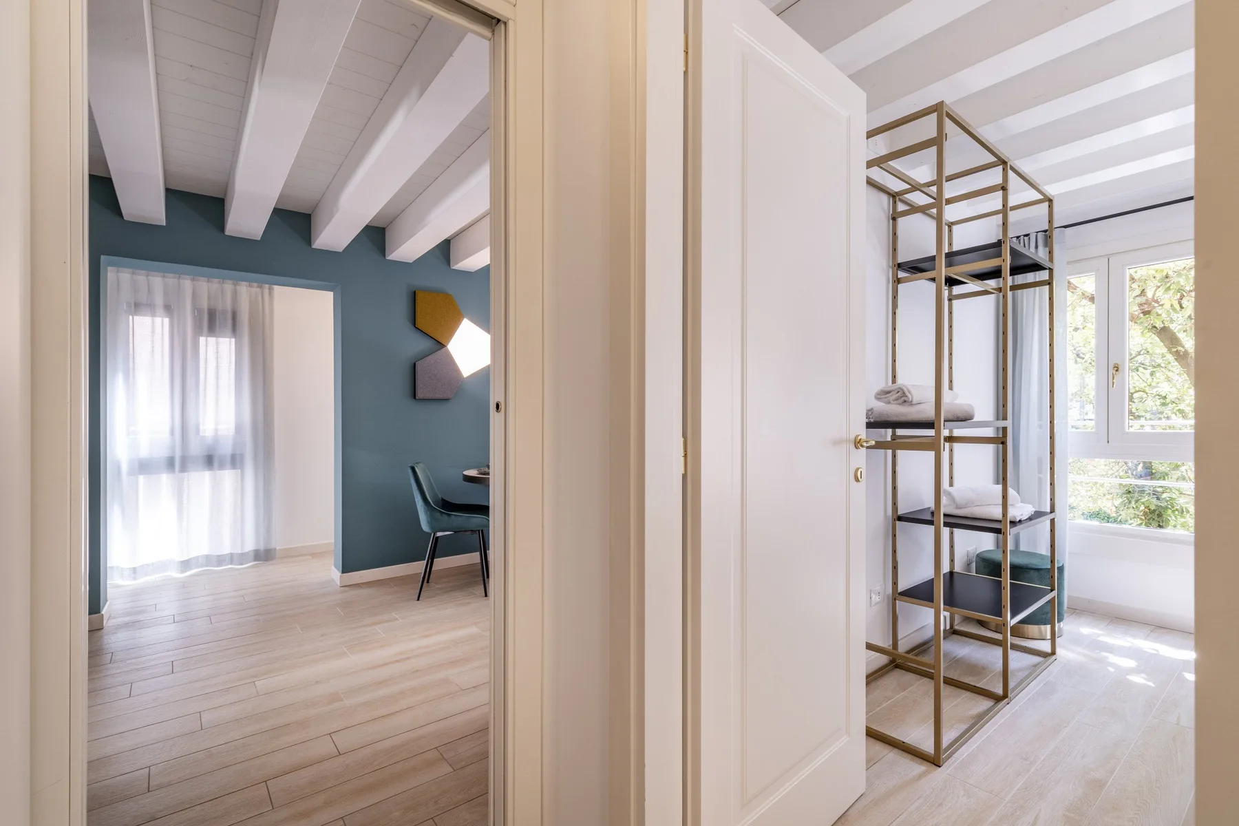 A bright interior hallway opens onto a room with seating and a room with shelving.