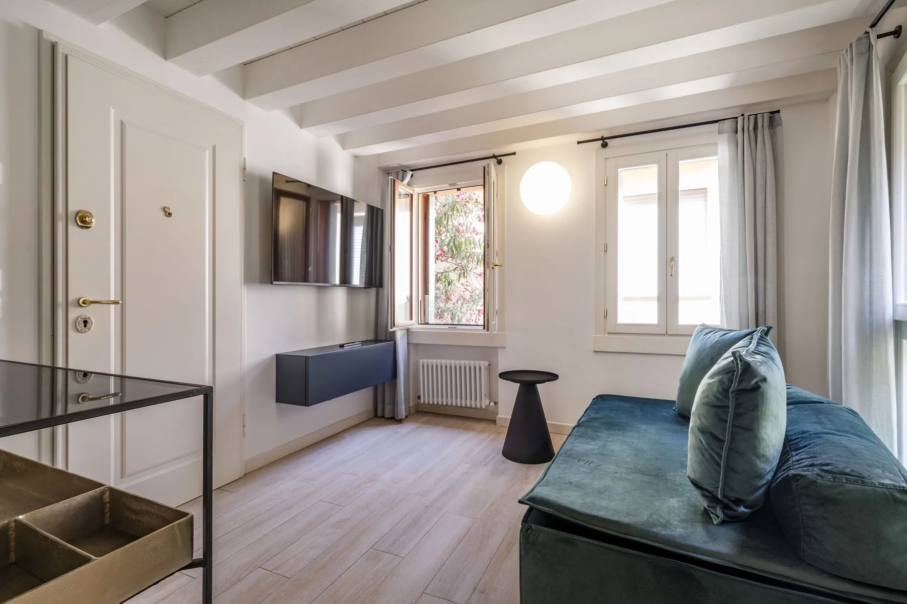 A bright room with blue seating, windows, and a wall-mounted television.