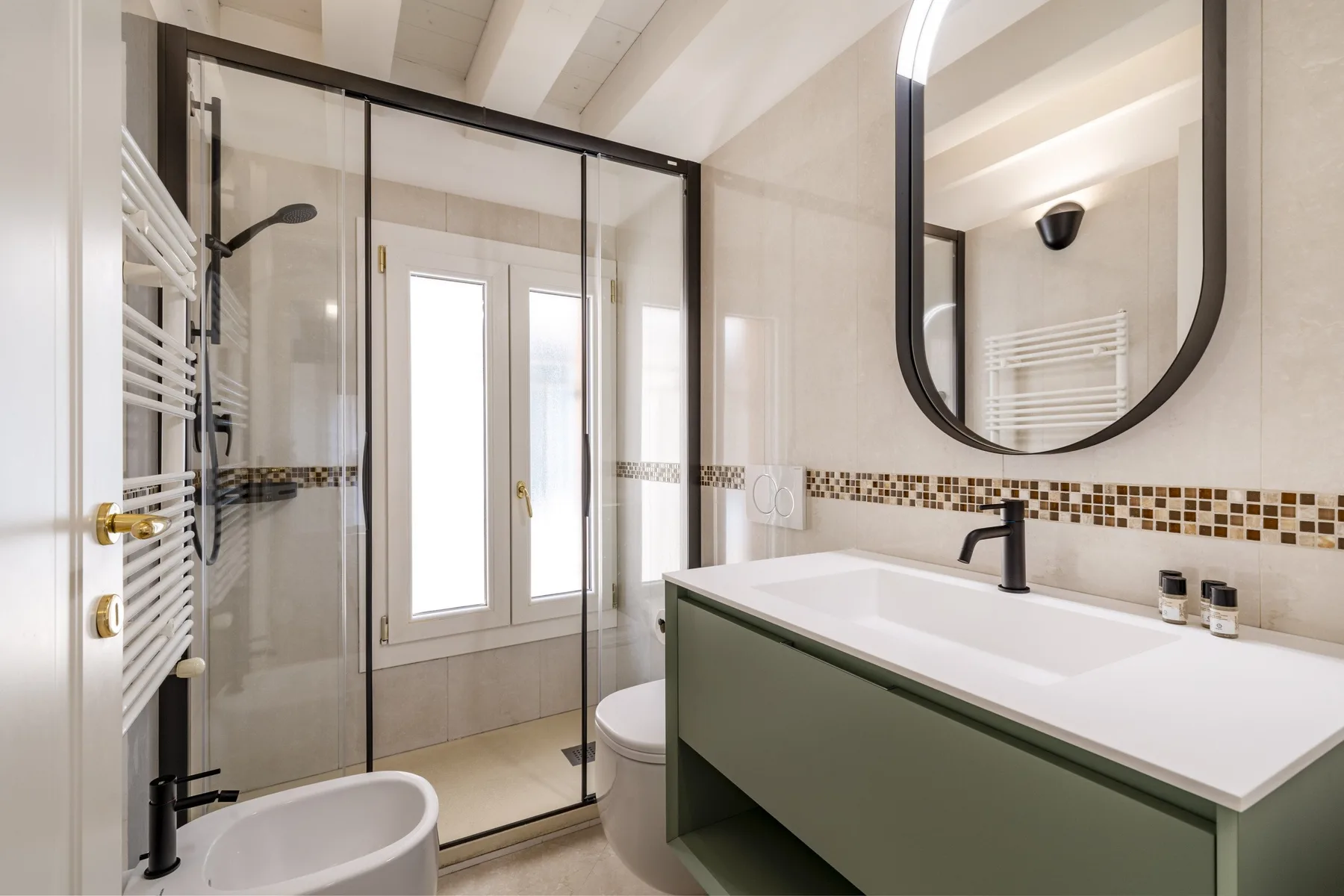 A bright bathroom with a glass shower, bathtub, and wide vanity.