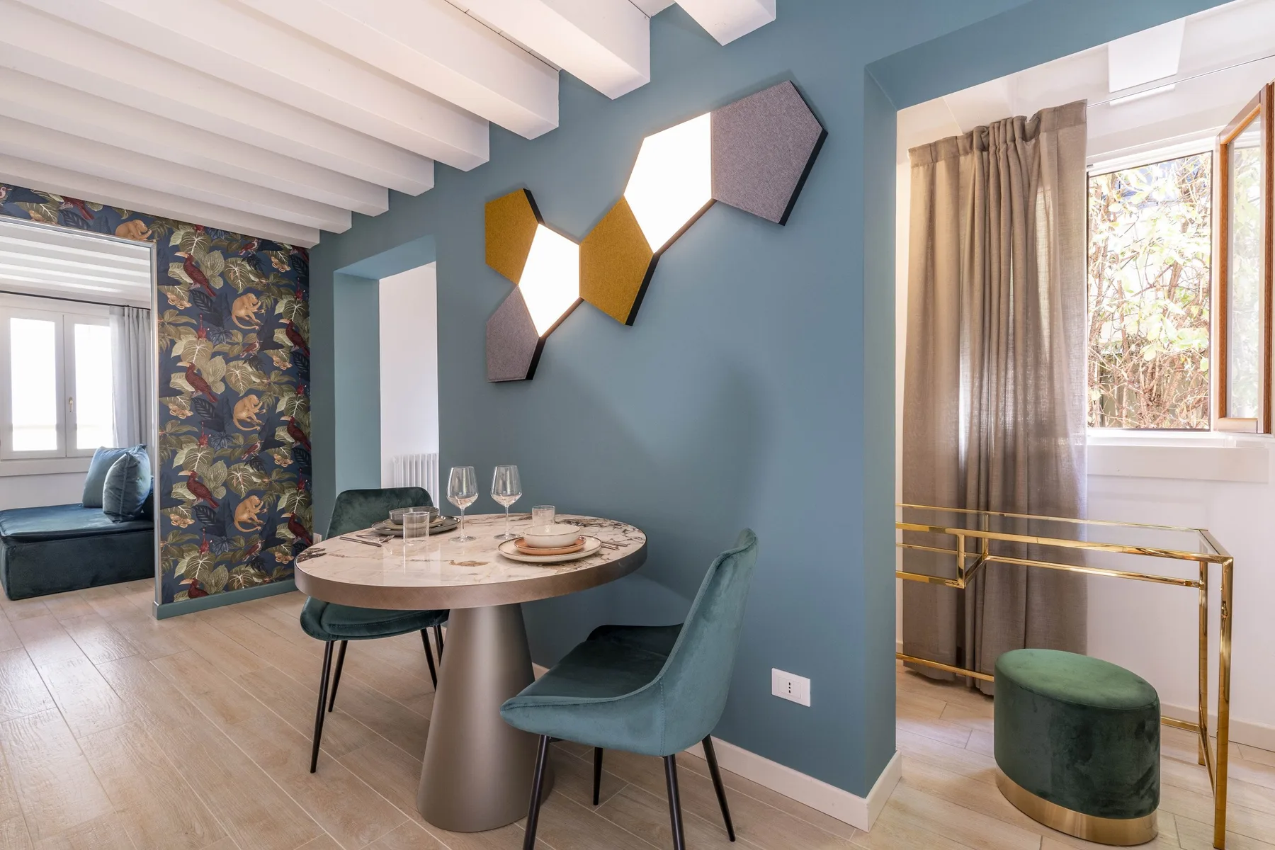 A dining area with a round table and teal seating beside a window.