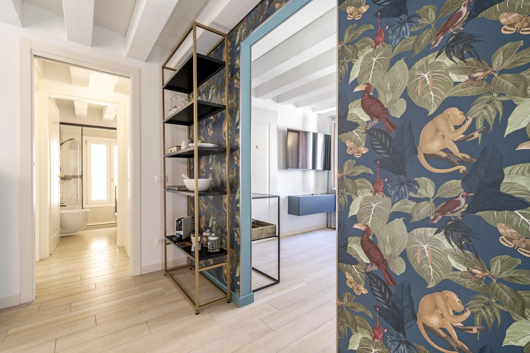 A bright interior hallway with open shelving and patterned wallpaper.