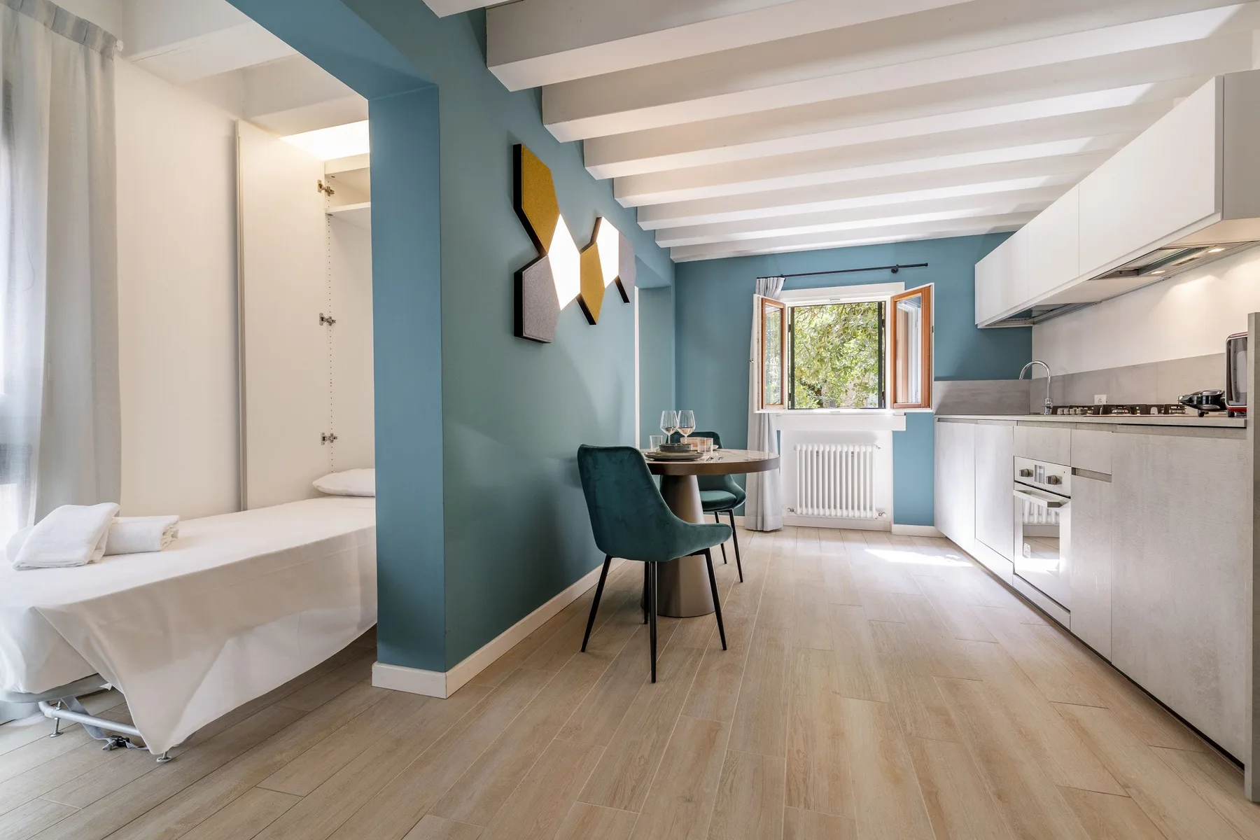 A compact room combines a bed, dining table, and kitchen along one wall.