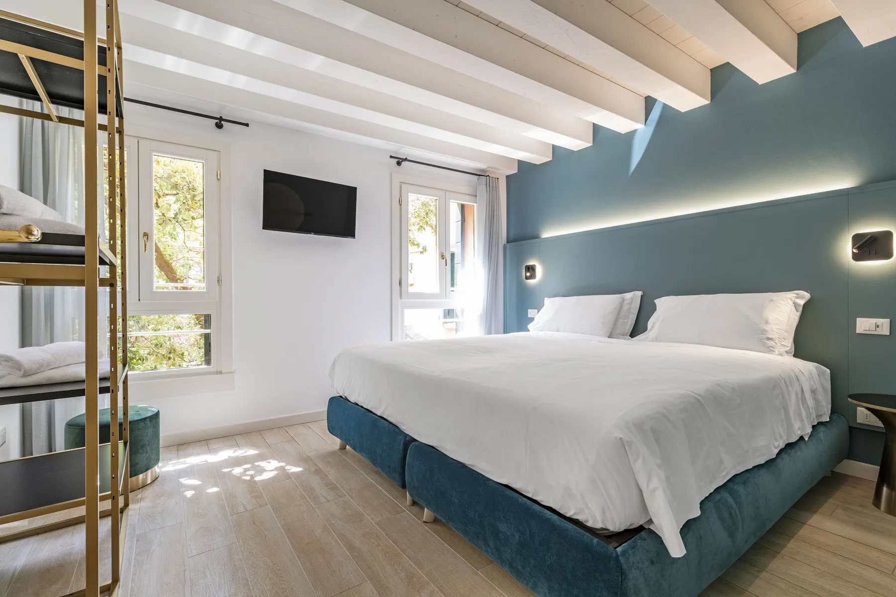 A bright bedroom with a large bed against a blue accent wall.