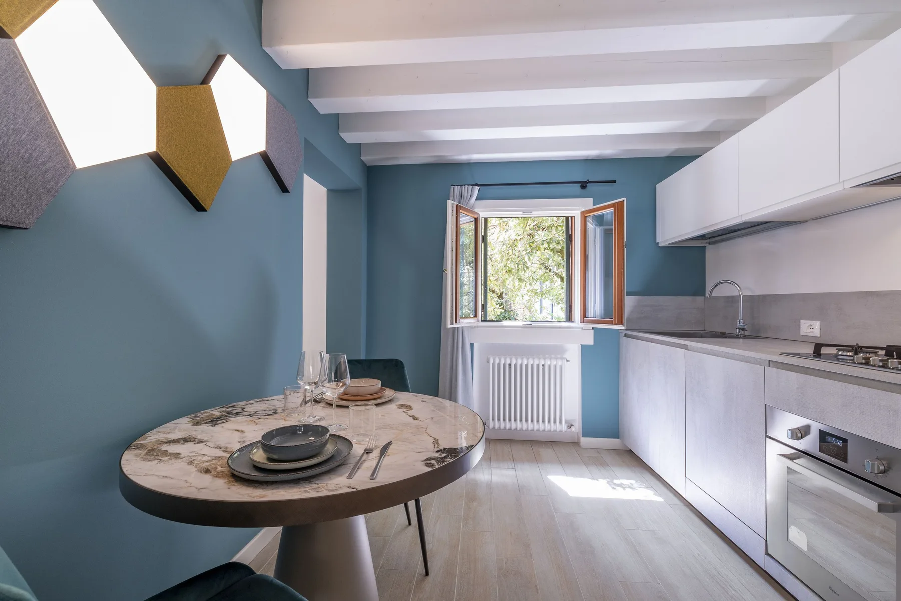 A modern kitchen with a round dining table and an open window.