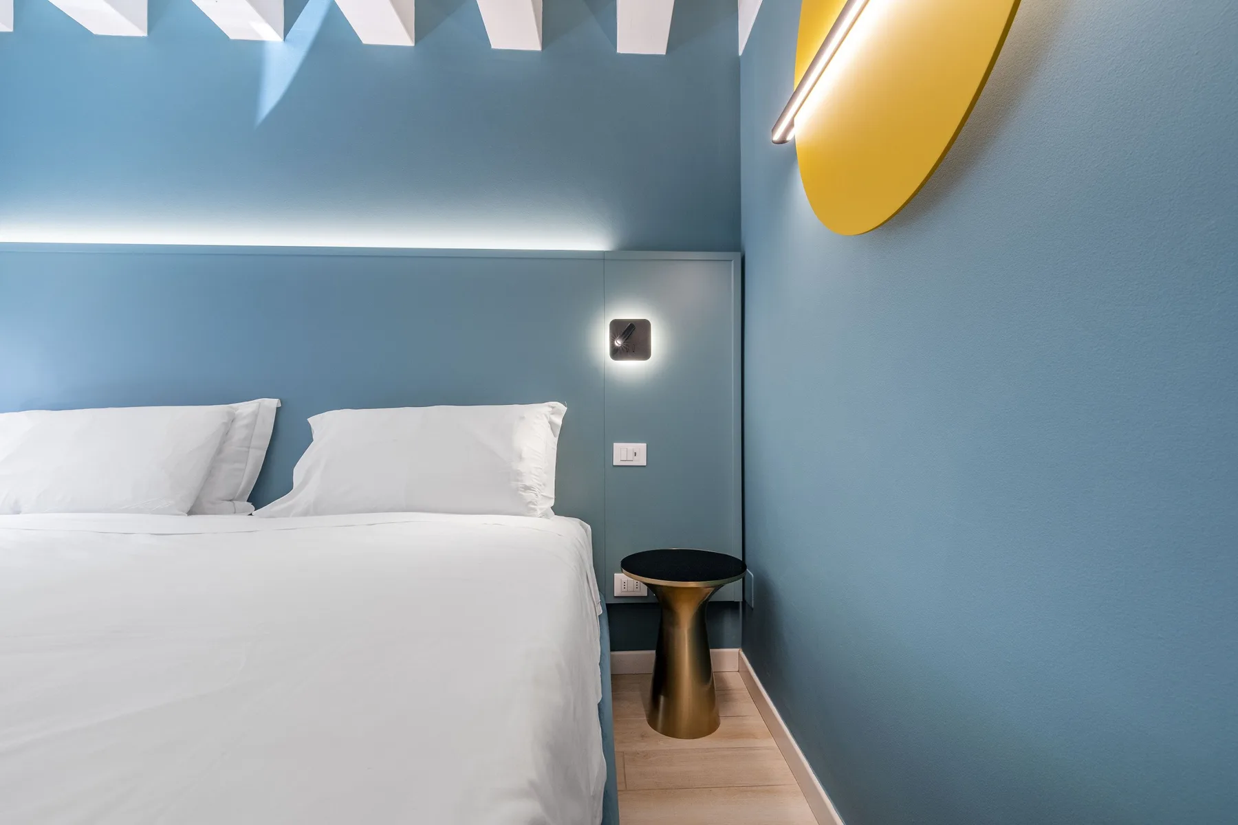 A bedroom with a neatly made bed against blue walls.