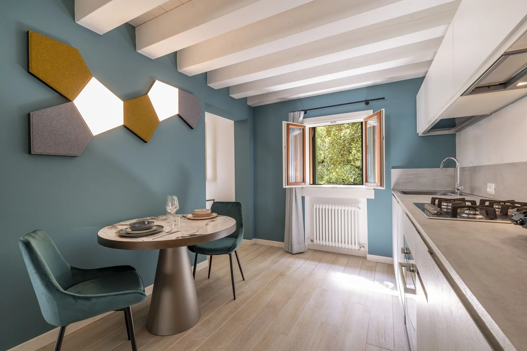 A dining area beside a kitchen, with a window overlooking greenery.