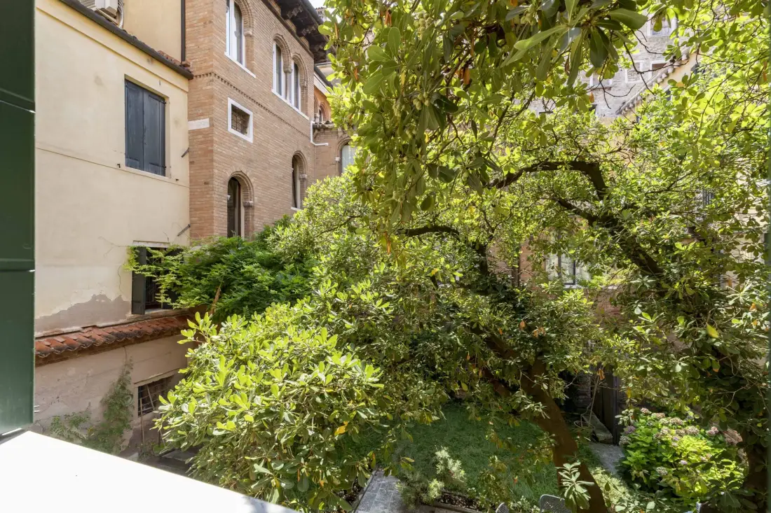 A leafy courtyard garden fills the space between surrounding buildings.