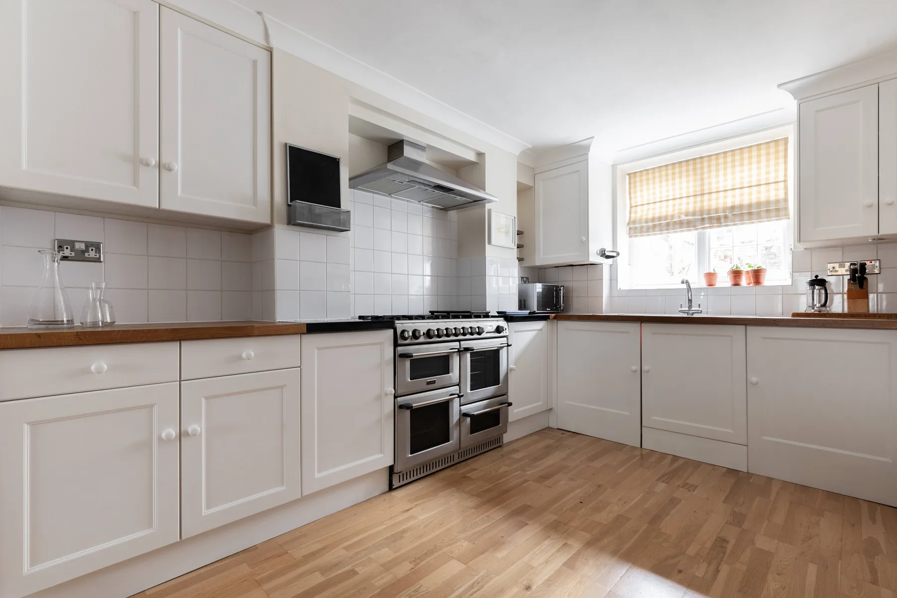 A bright kitchen with white cabinetry, a stainless-steel range, and a window.