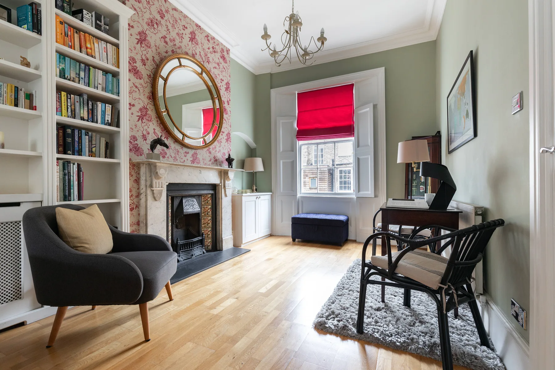 A bright living room with bookshelves, a fireplace, and a desk beside the window.