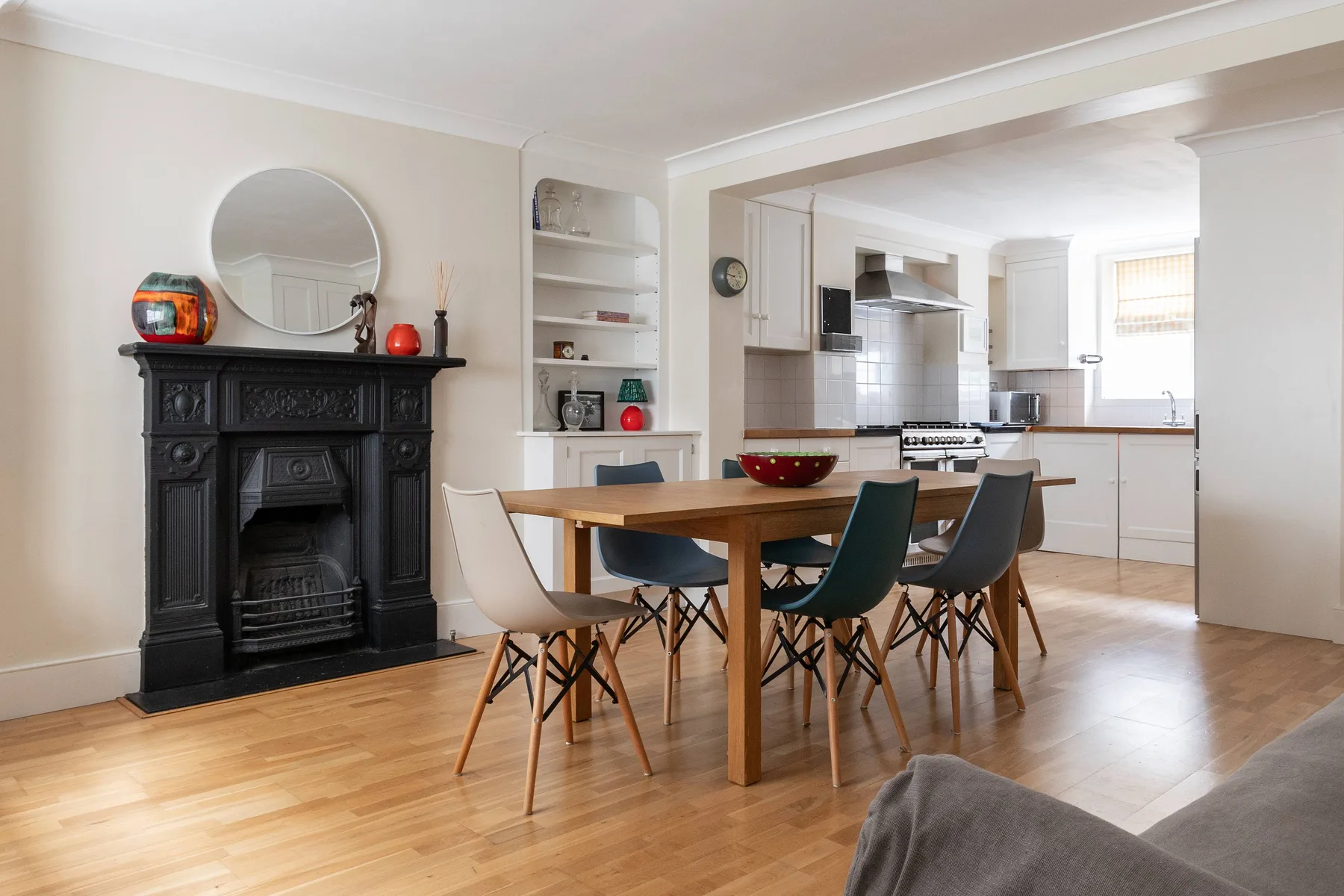 A dining area with a wooden table and chairs beside a black fireplace.