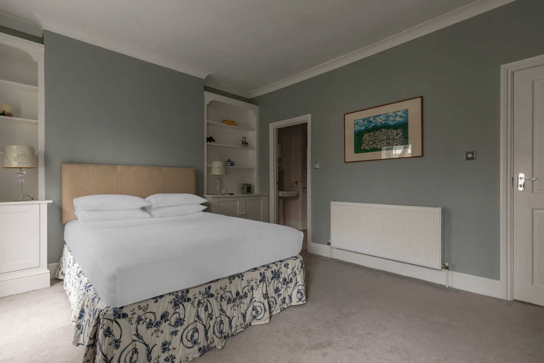 A bedroom with a bed, built-in shelving, and a framed picture.