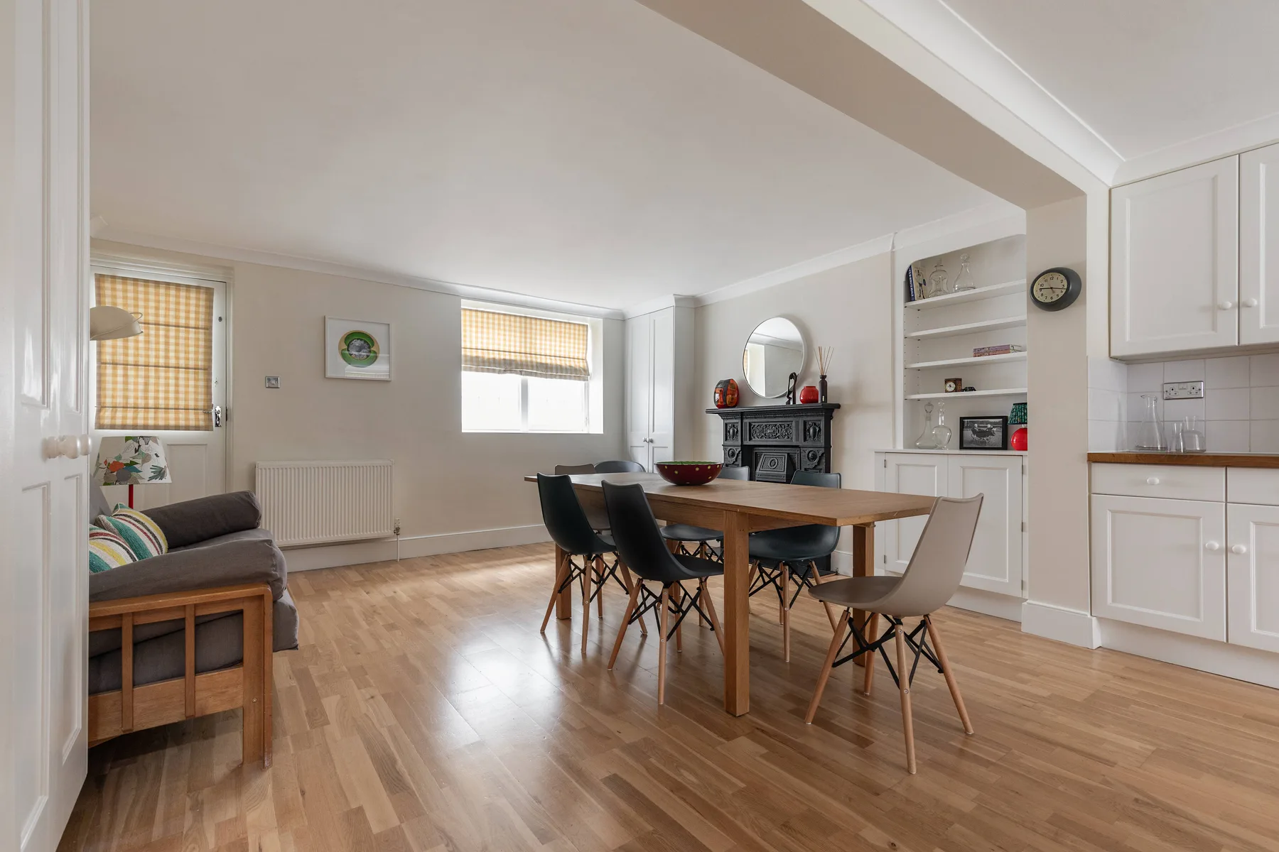 A dining area with a wooden table and seating beside a compact kitchen.