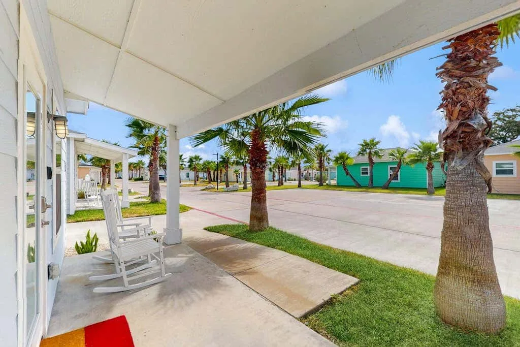 Una zona de estar exterior cubierta da a un patio pavimentado con palmeras.