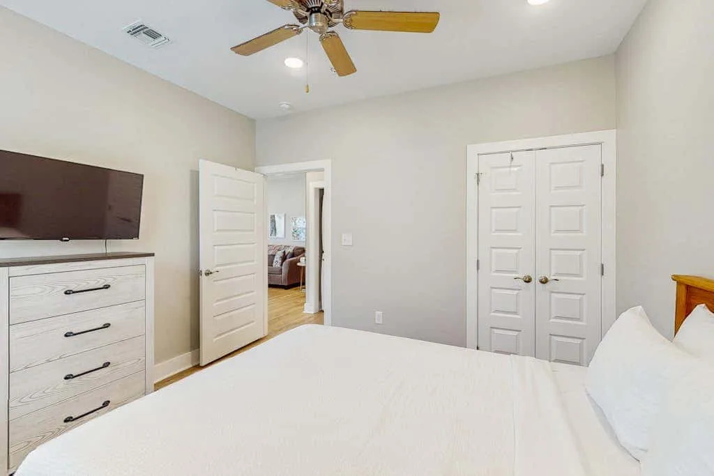 Un dormitorio con cama, cómoda y ventilador de techo.