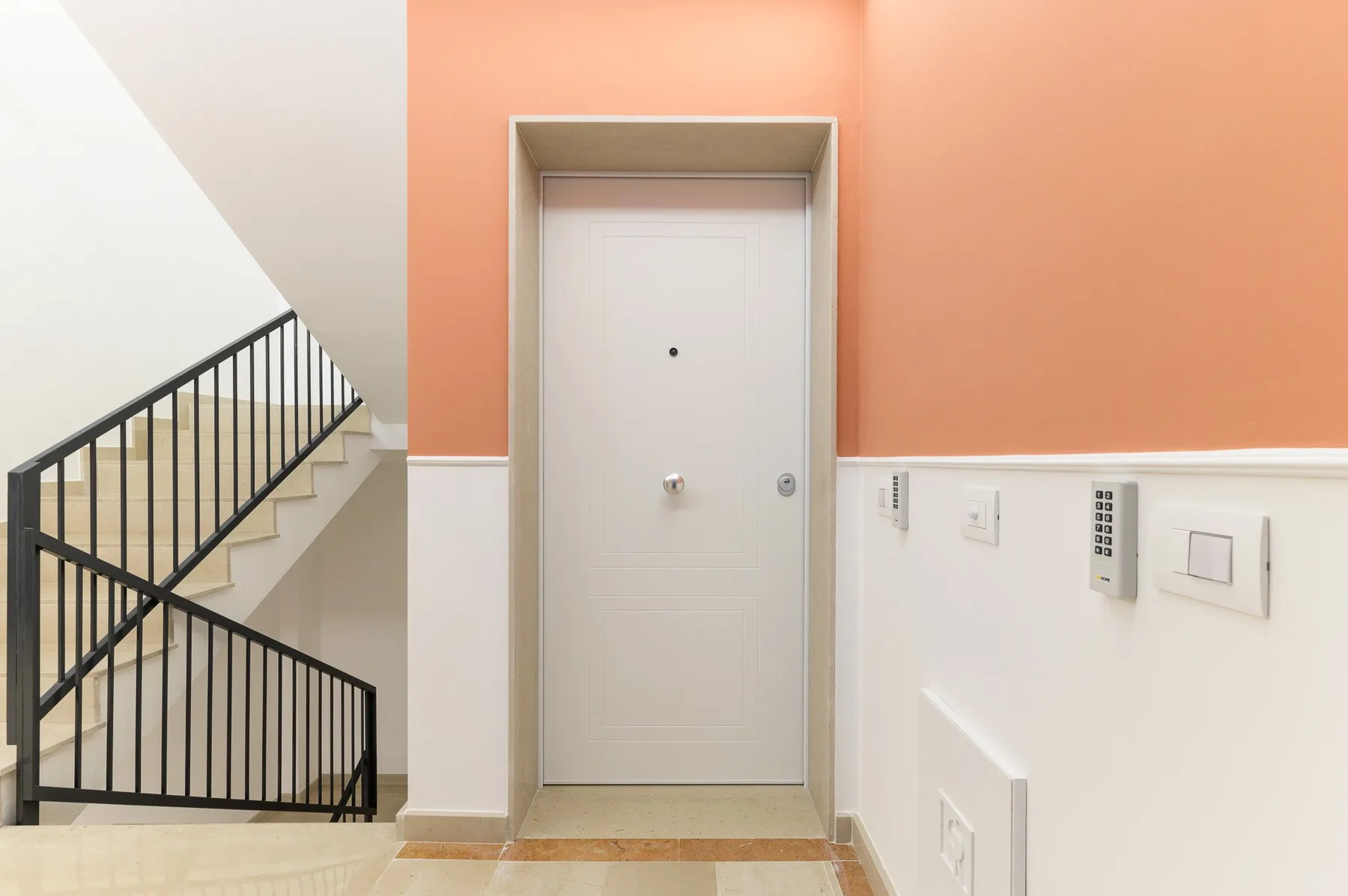 Un pasillo de edificio con una puerta cerrada y una escalera al lado.