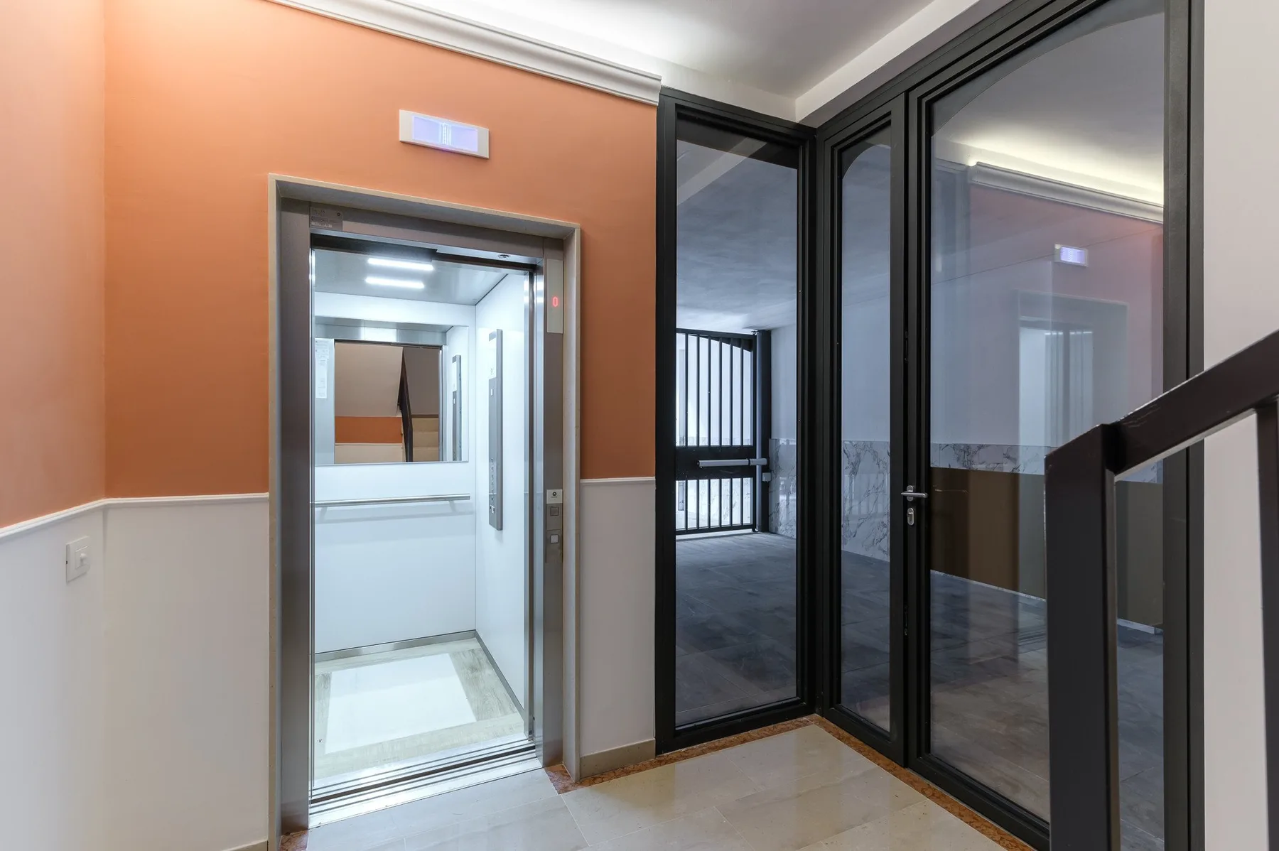 Un pasillo moderno con una puerta de vidrio y ventanas con marcos negros.