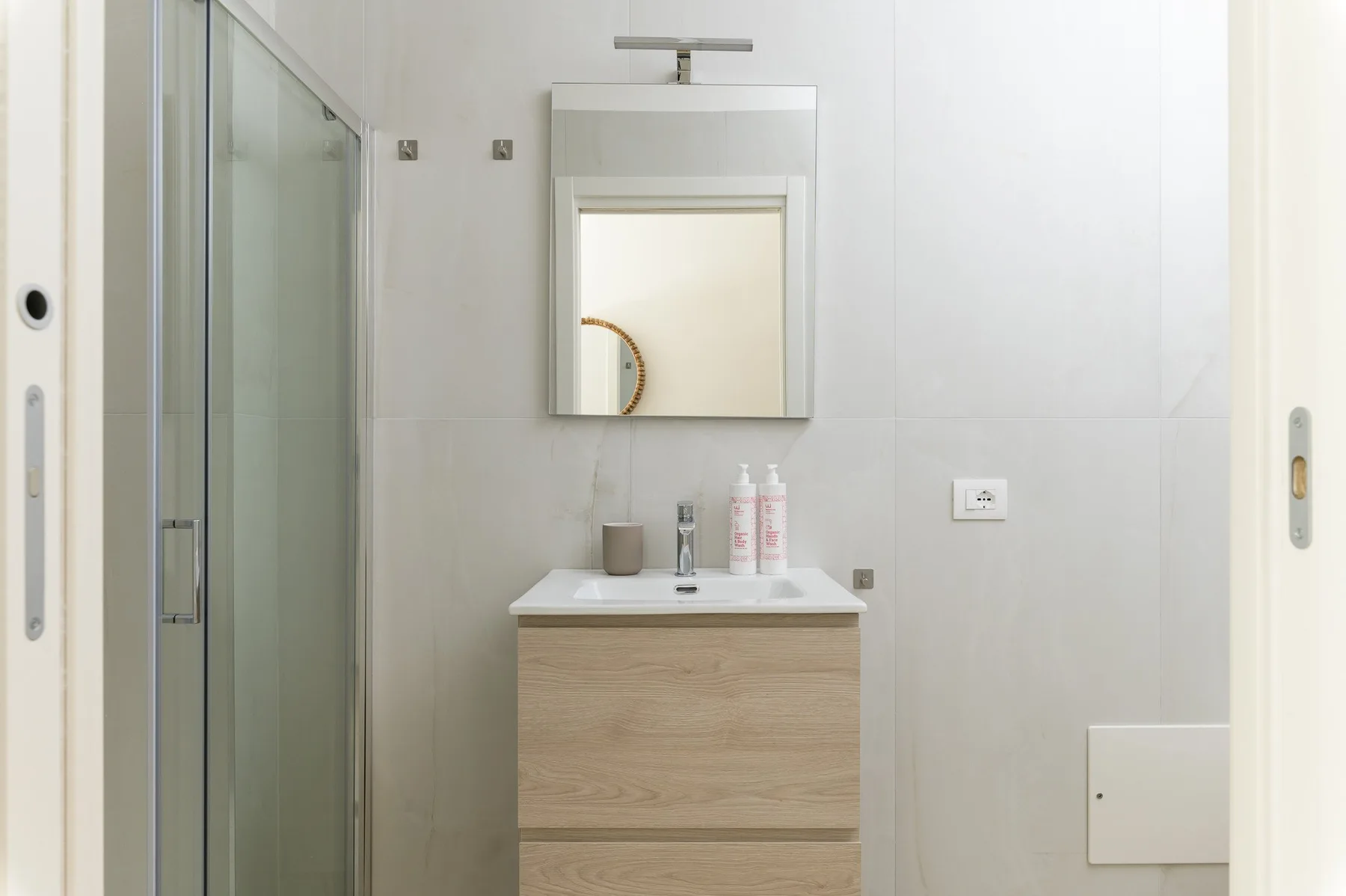 Un lavabo de baño con espejo y una ducha con mampara de vidrio.