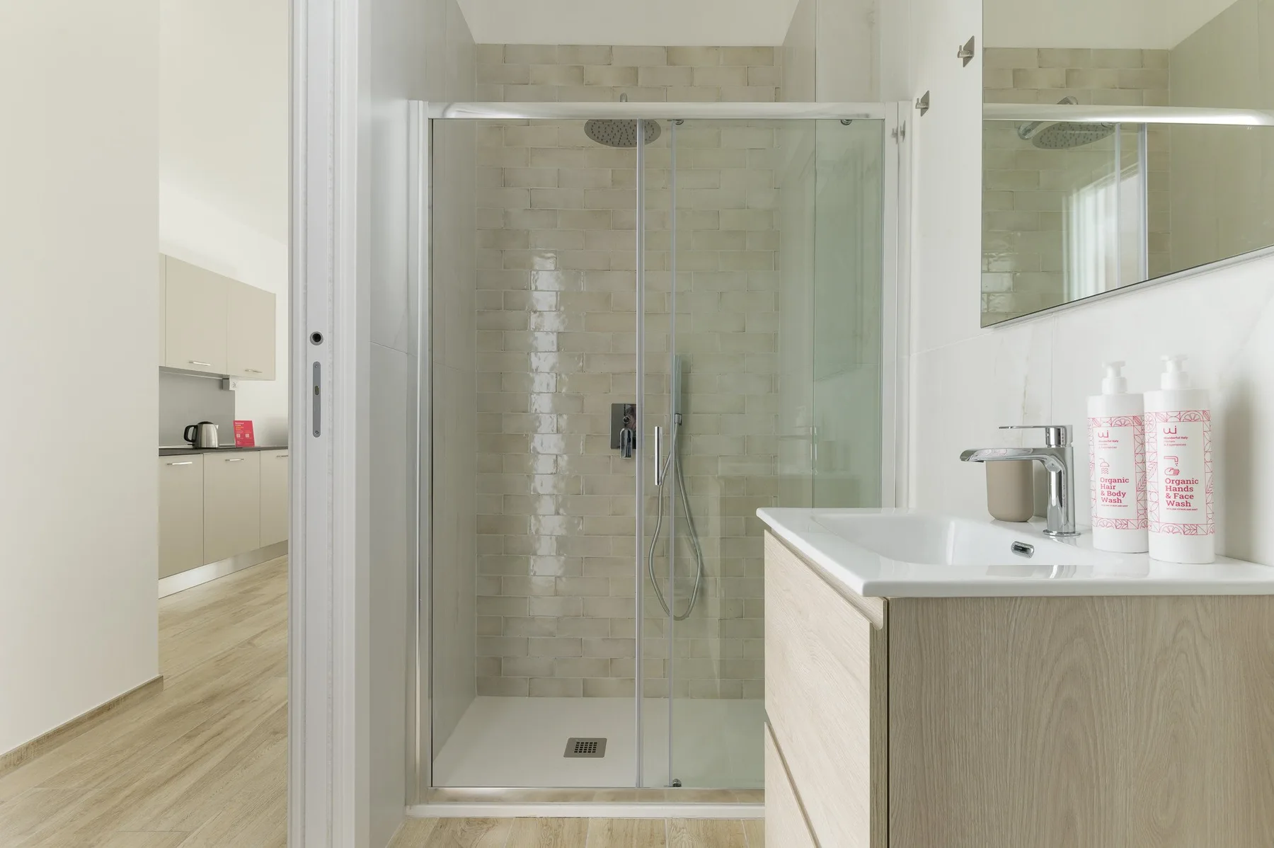 Un baño luminoso con una ducha de vidrio y un lavabo.