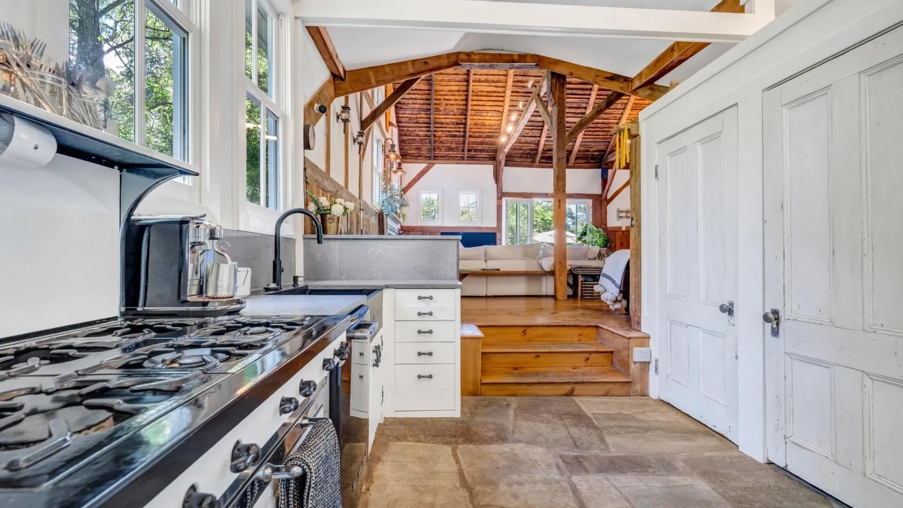 A kitchen opens onto a raised living area with exposed wooden beams.