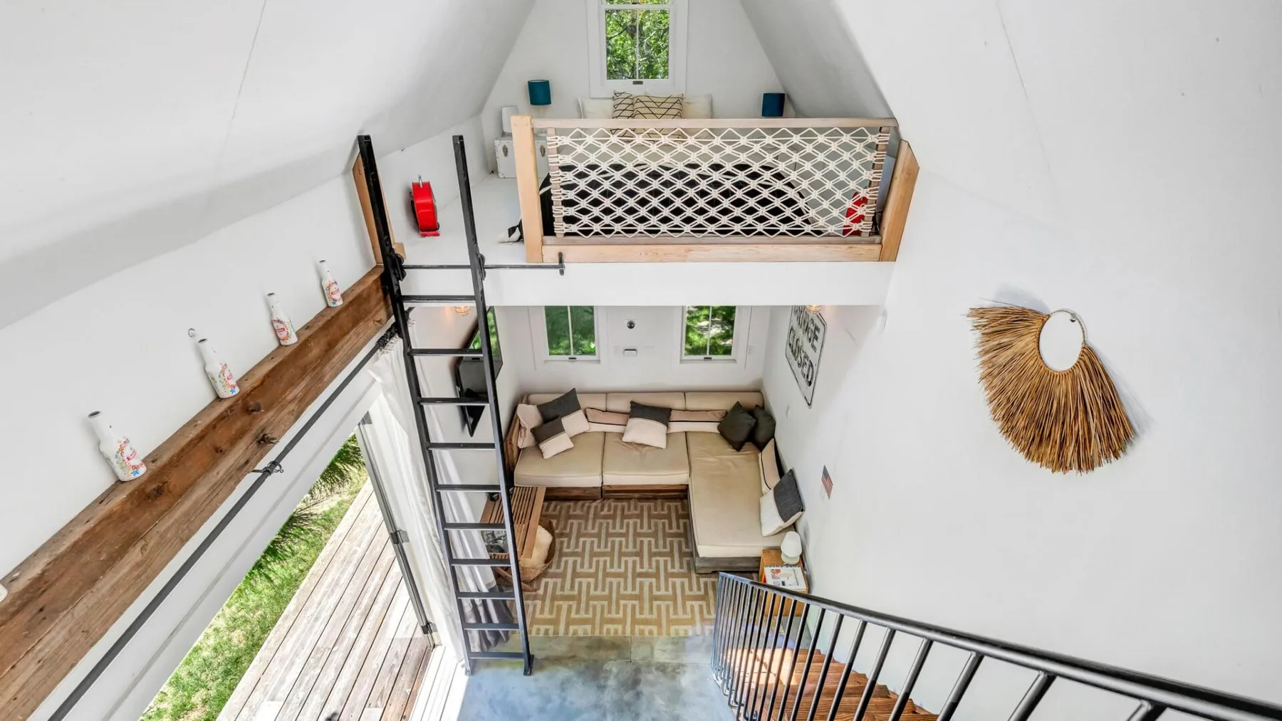 A bright loft living area with a raised sleeping platform and ladder.