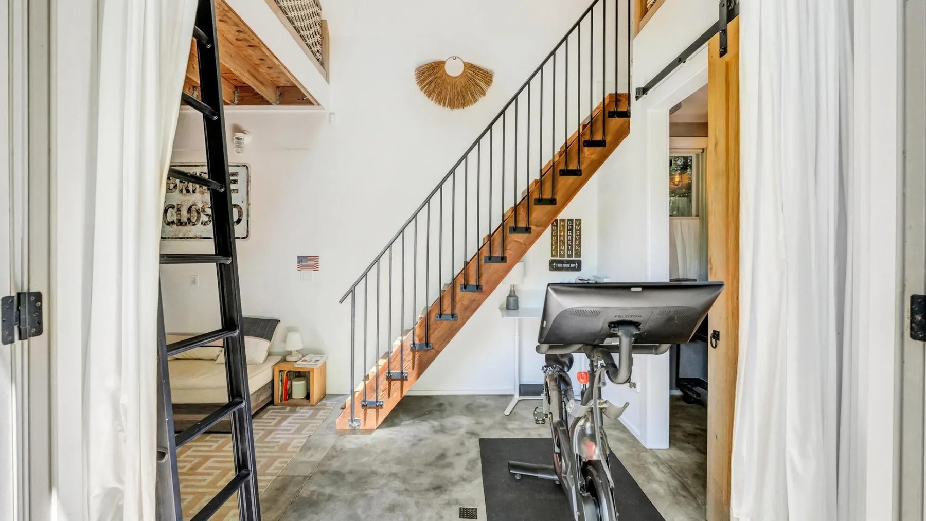A bright interior with a staircase and exercise bike.