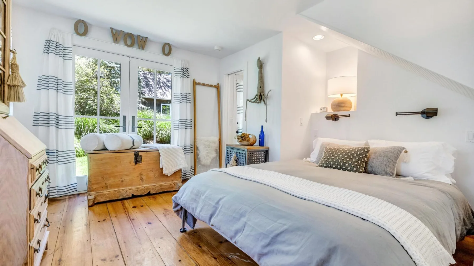 A bright bedroom with a large bed and windows overlooking greenery.