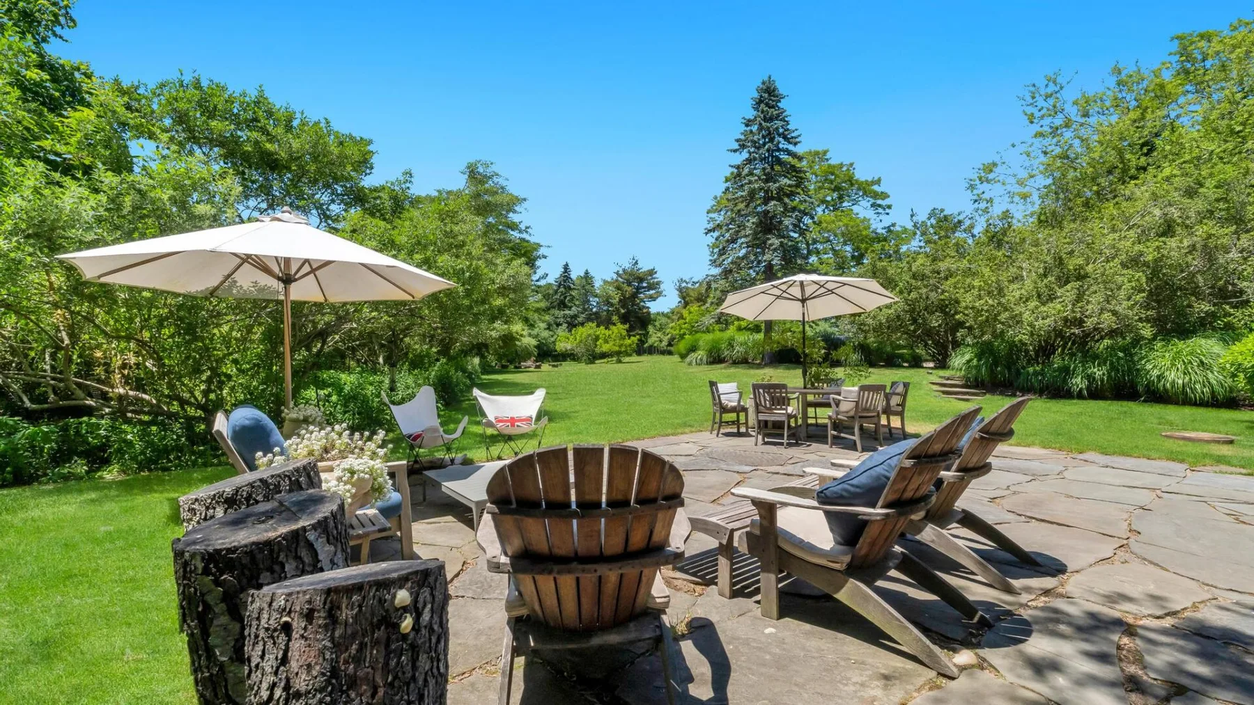 An outdoor patio with seating and umbrellas overlooks a green lawn.