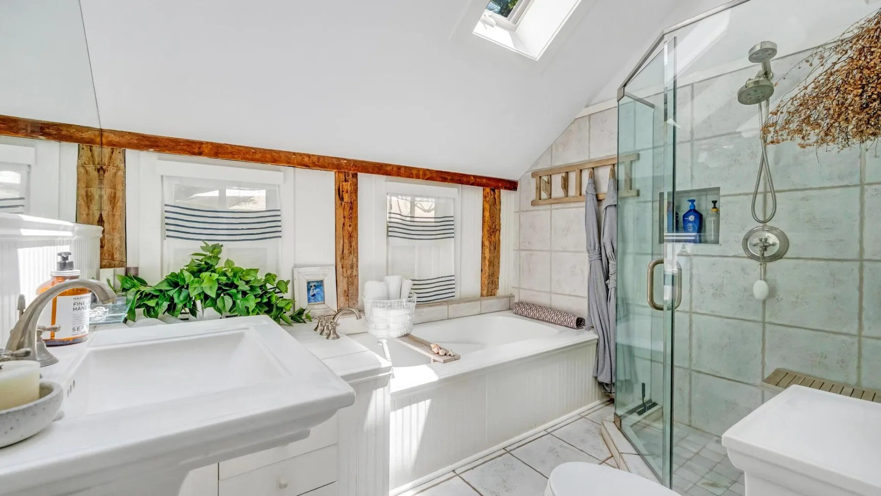 A bright bathroom with a bathtub, sink, and glass shower.