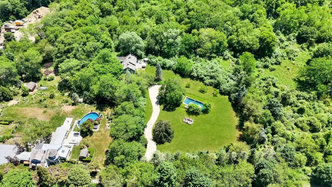 An aerial view of a green property with a winding path and surrounding trees.