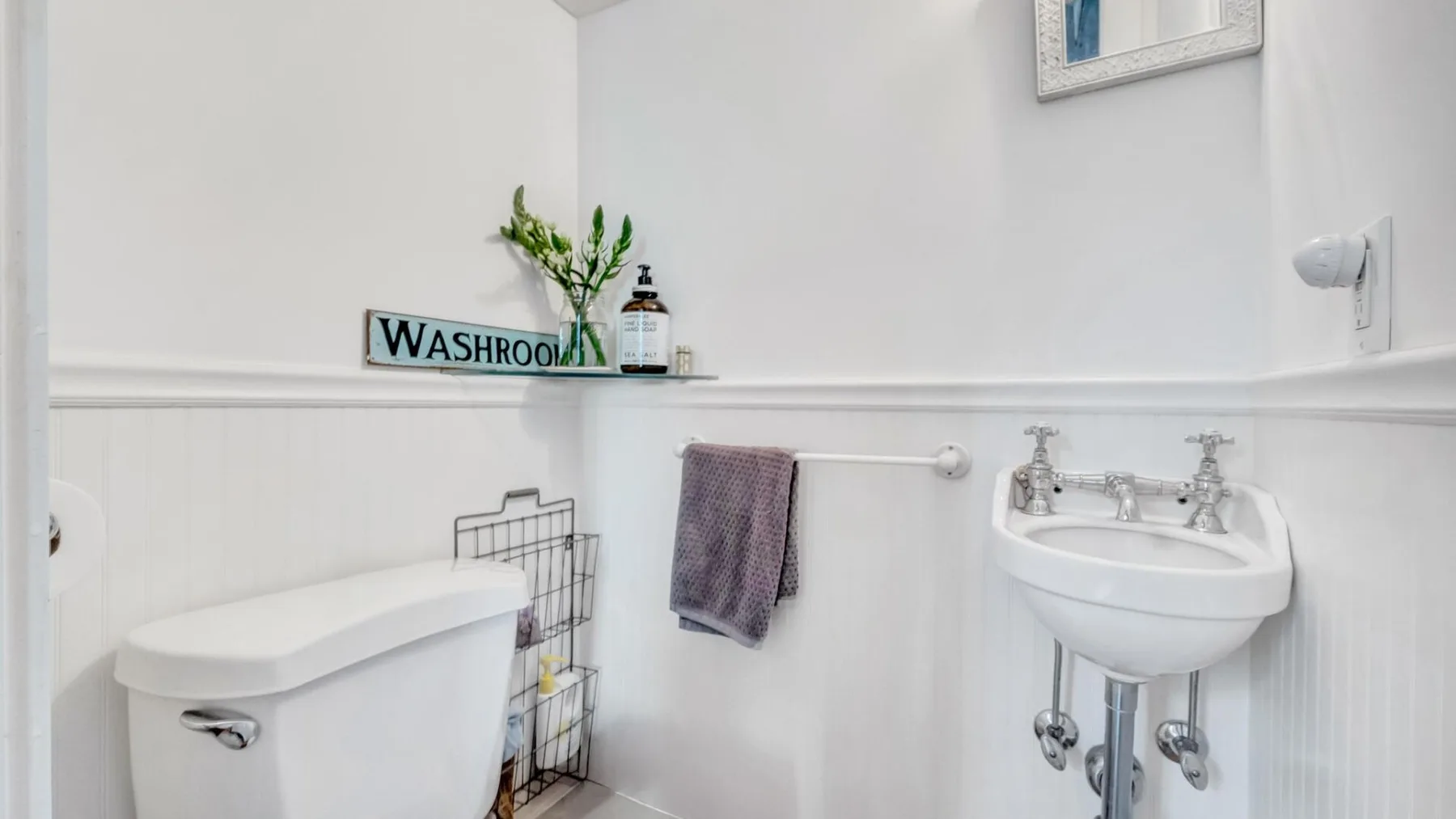 A bright bathroom with a pedestal sink and toilet.