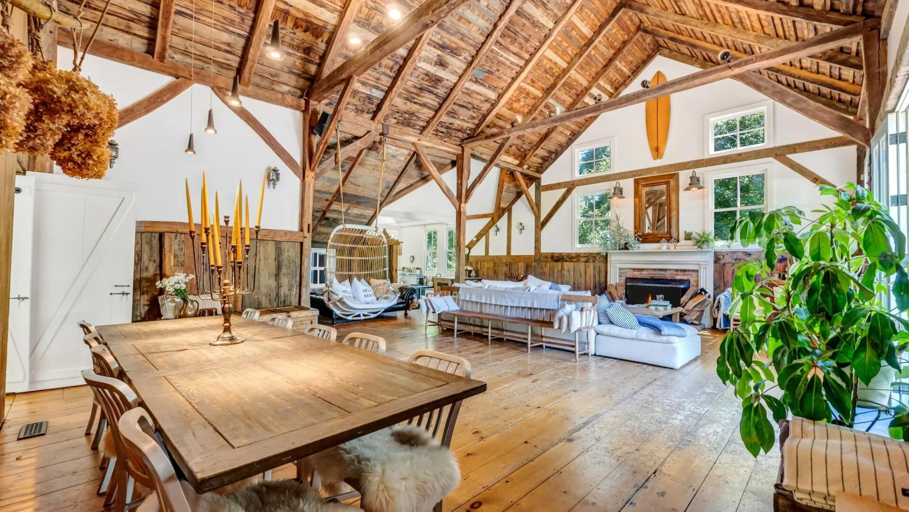 A spacious living room with a high timber ceiling and seating around a fireplace.