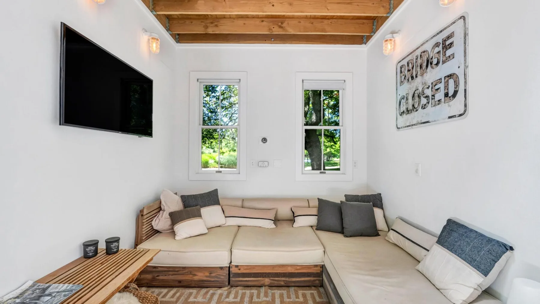 A bright lounge with built-in seating, windows, and a wall-mounted television.