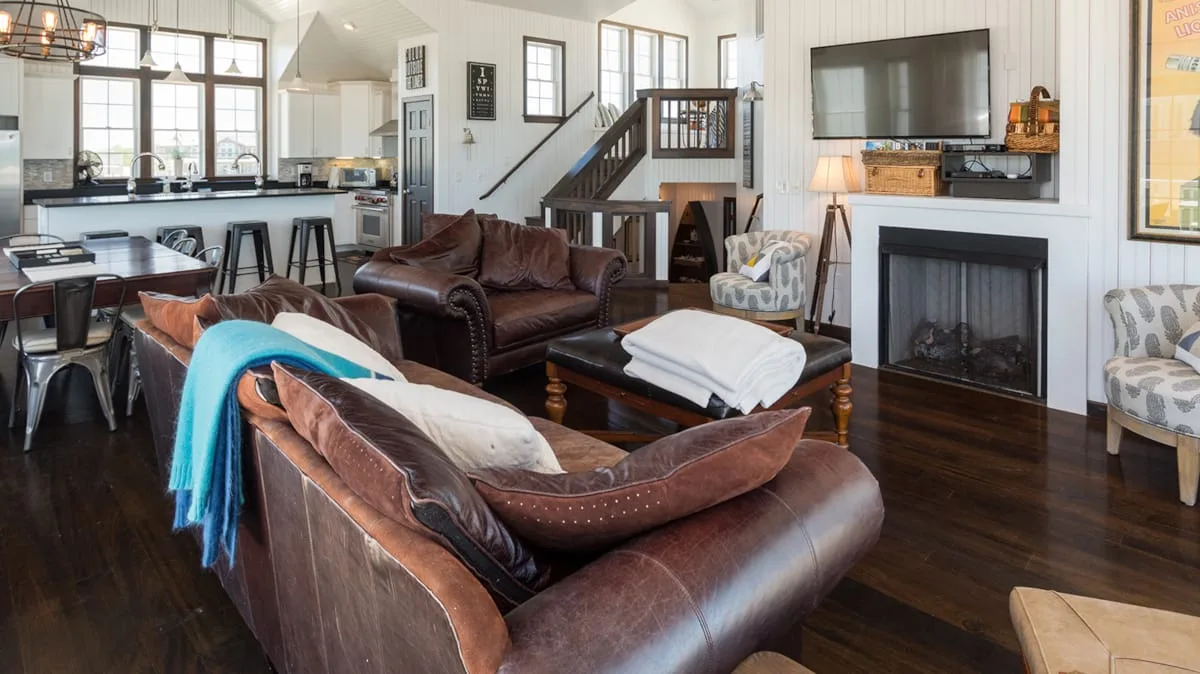 A bright open-plan living room with brown seating and a fireplace.